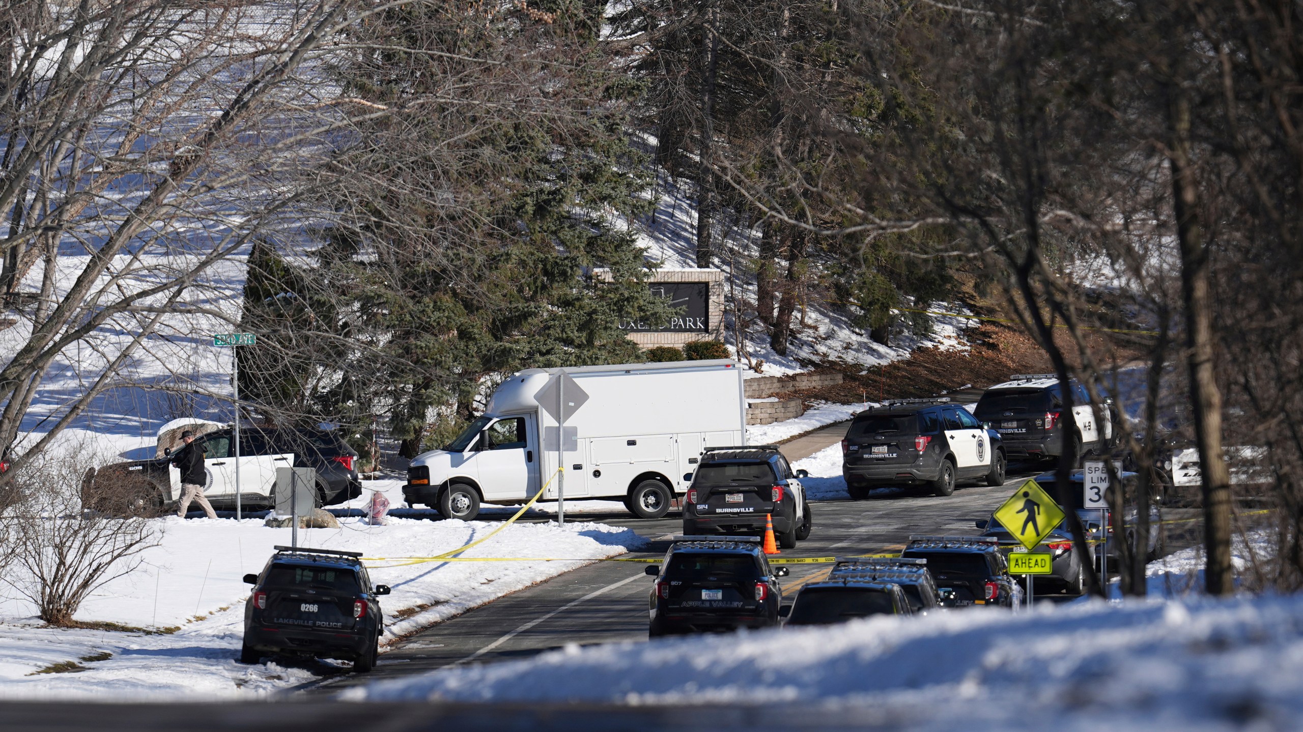 FILE - Law enforcement vehicles are parked near the scene where two police officers and a first responder were shot and killed, Feb. 18, 2024, in Burnsville, Minn. A woman has been charged with illegally buying guns used in the killings of the three Minnesota first responders in a standoff at a home in Burnsville, where seven children were inside, U.S. Attorney Andrew M. Luger announced Thursday, March 14, at a news conference. (AP Photo/Abbie Parr, File)