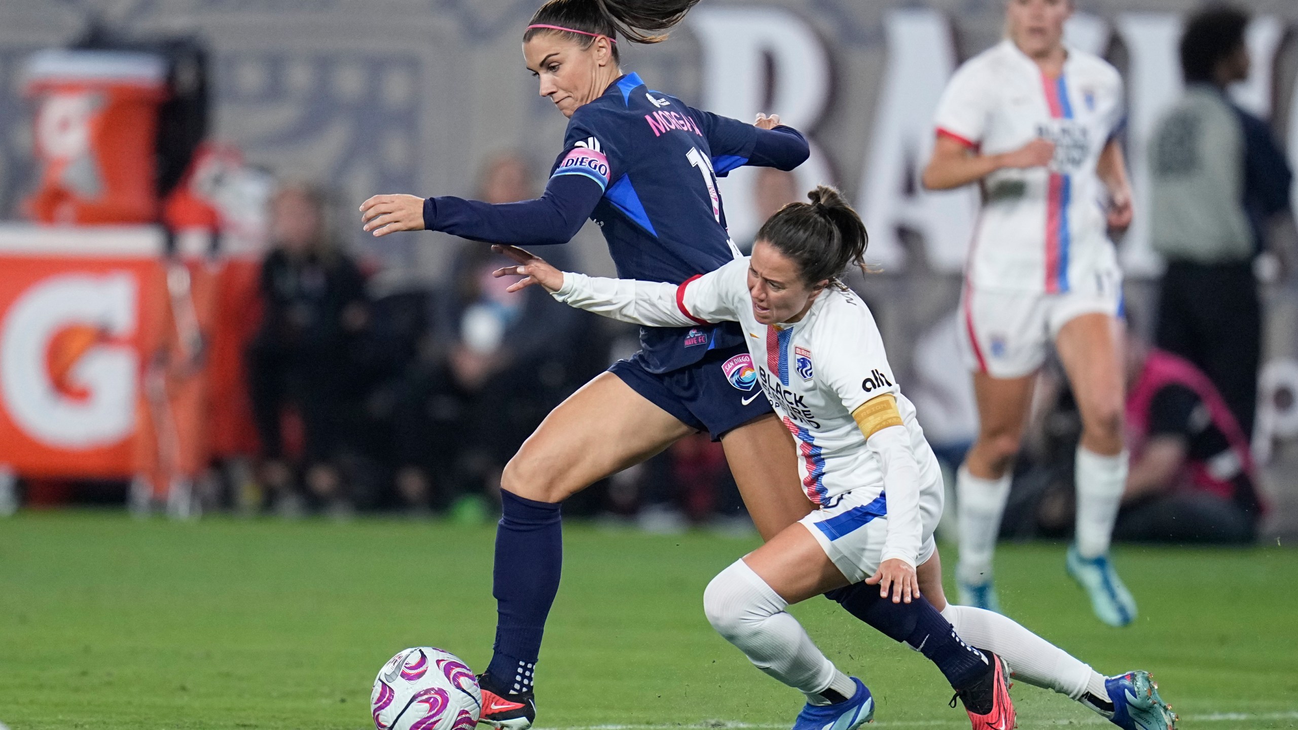 FILE - San Diego Wave forward Alex Morgan, left, controls the ball as OL Reign defender Lauren Barnes defends during the second half of an NWSL semifinal playoff soccer match Sunday, Nov. 5, 2023, in San Diego. The National Women's Soccer League has a lot to be excited about heading into its 11th season. (AP Photo/Gregory Bull, File)