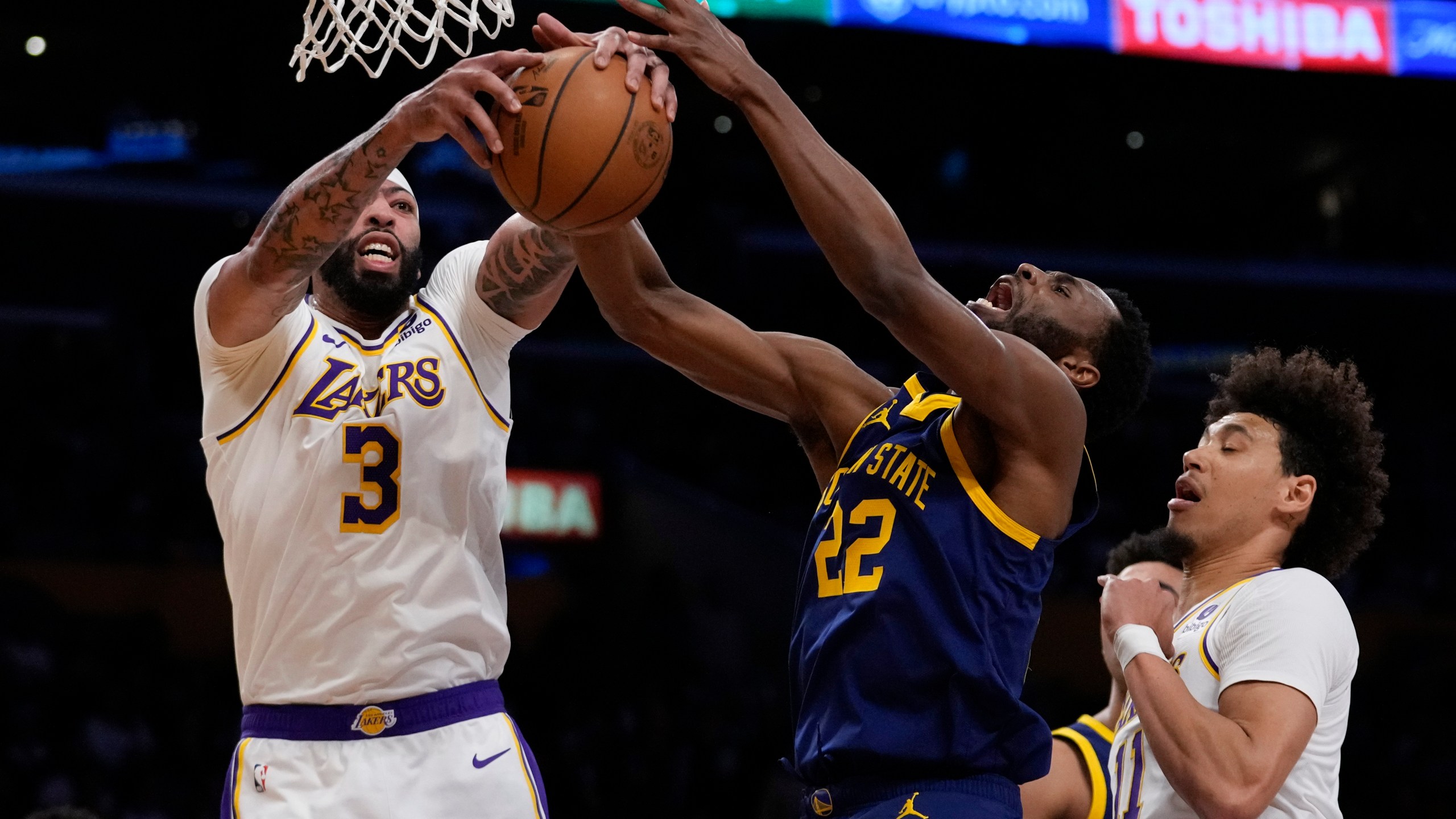 Los Angeles Lakers forward Anthony Davis (3) and Golden State Warriors forward Andrew Wiggins (22) reach for a rebound during the first half of an NBA basketball game in Los Angeles, Saturday, March 16, 2024. (AP Photo/Ashley Landis)