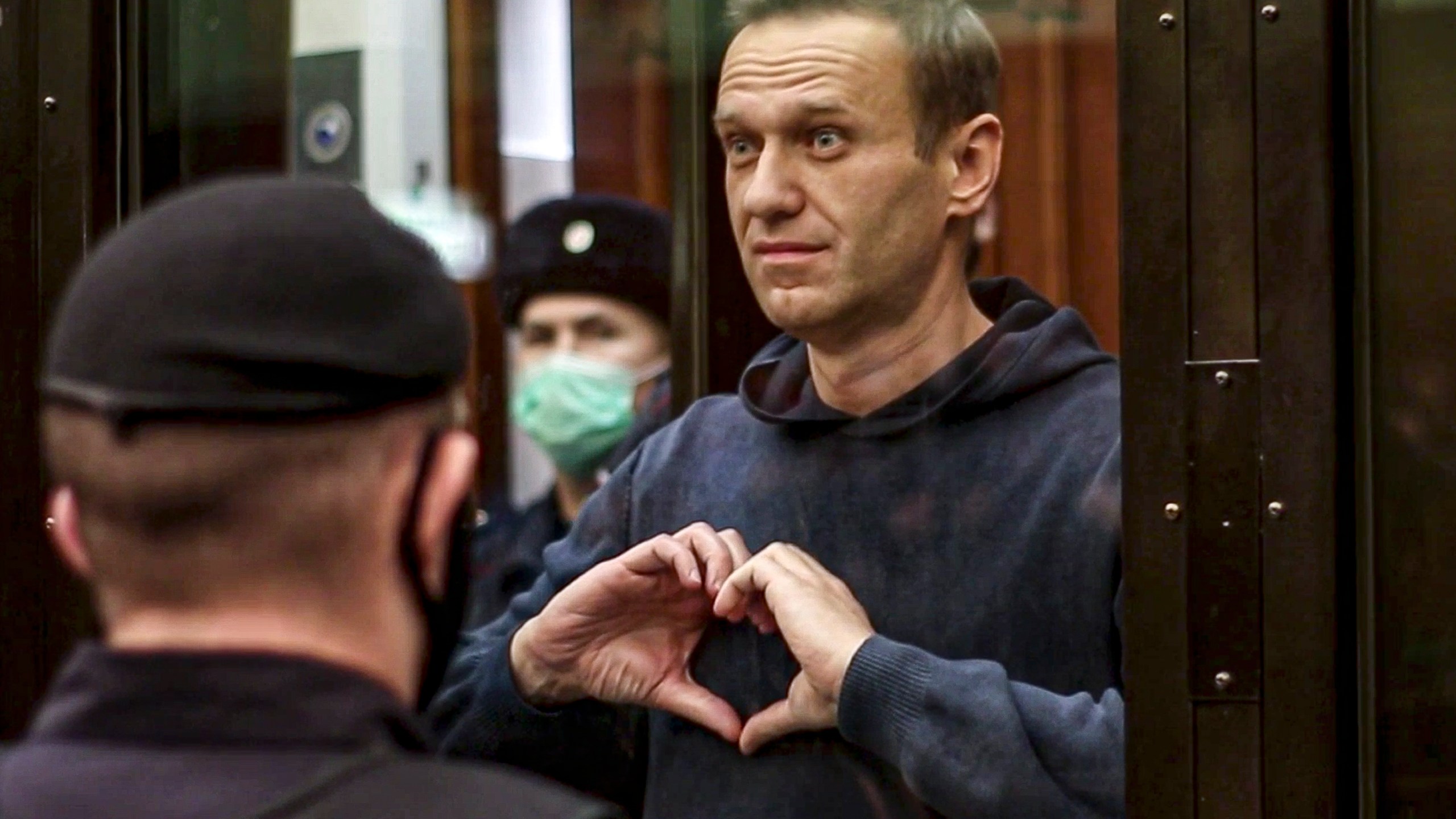 FILE - In this handout photo taken from video provided by the Moscow City Court on Feb. 2, 2021, Russian opposition leader Alexei Navalny shows a heart symbol while standing in a defendants' cage during a hearing in the Moscow City Court in Moscow, Russia. President Vladimir Putin says he supported an idea to release Navalny in a prisoner exchange just days before the man who was his biggest foe died. (Moscow City Court via AP, File)
