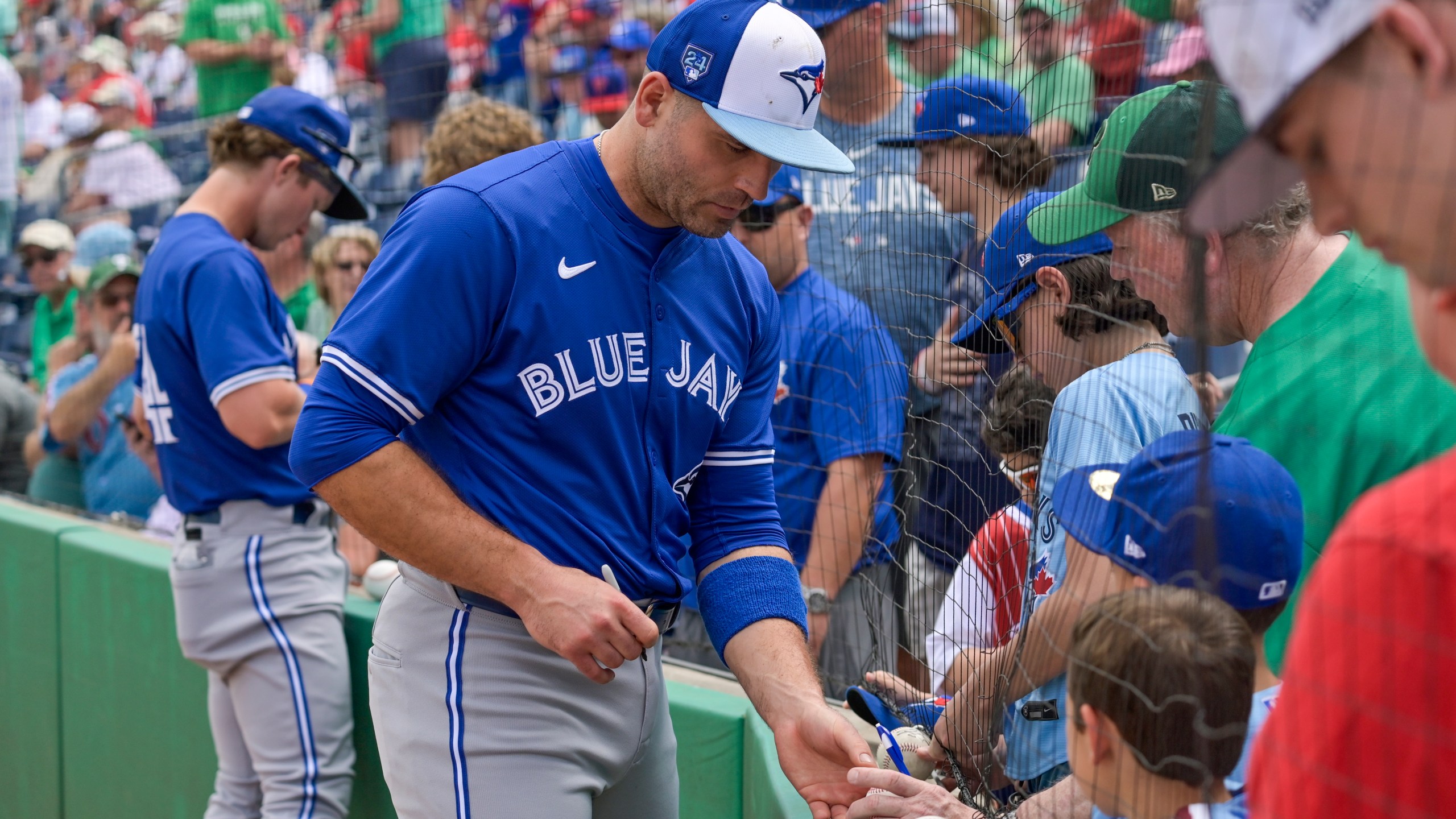Toronto Blue Jays' Joey Votto, center, signs autographs before a spring training baseball game against the Philadelphia Phillies Sunday, March 17, 2024, in Clearwater, Fla. (Steve Nesius/The Canadian Press via AP)