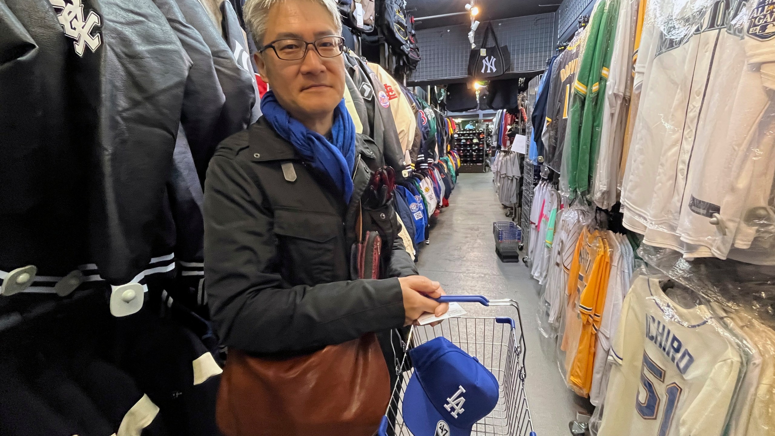 Hideki Chiba has a blue Dodgers cap in his basket, a gift for his father-in-law, as he shops on Monday Feb 26, 2024, at a sporting goods store, "SELECTION," in Shinjuku district in Tokyo. (AP Photo/Stephen Wade)