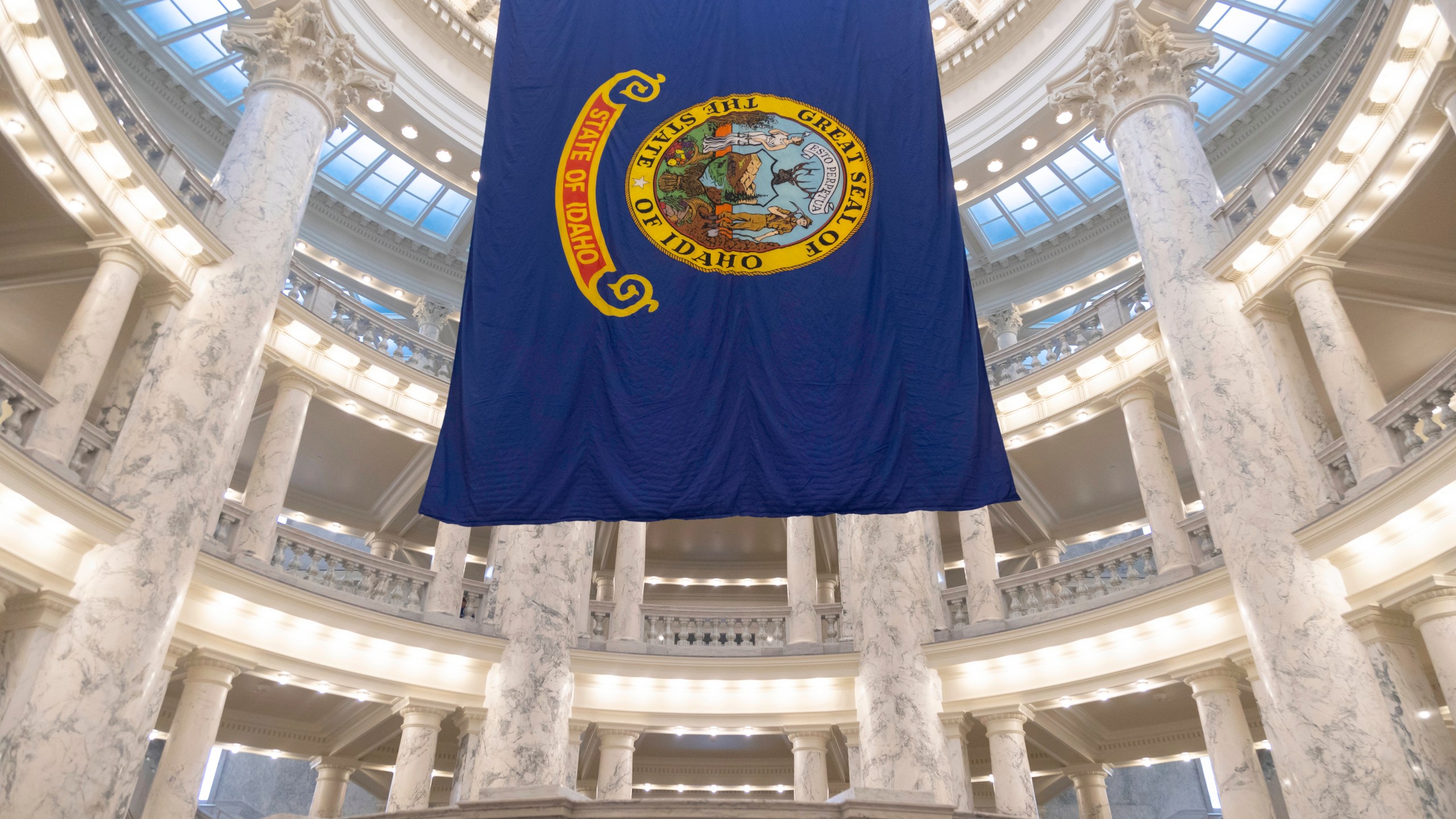 FILE - The Idaho state flag hangs in the State Capitol in Boise, Idaho, Jan. 9, 2023. The Idaho Senate is expected to take a final vote on Monday, March 18, 2024, on a bill that would prohibit transgender and nonbinary Idahoans enrolled in Medicaid, or state employees enrolled in the state's insurance plan, from obtaining gender-affirming care. (AP Photo/Kyle Green, File)