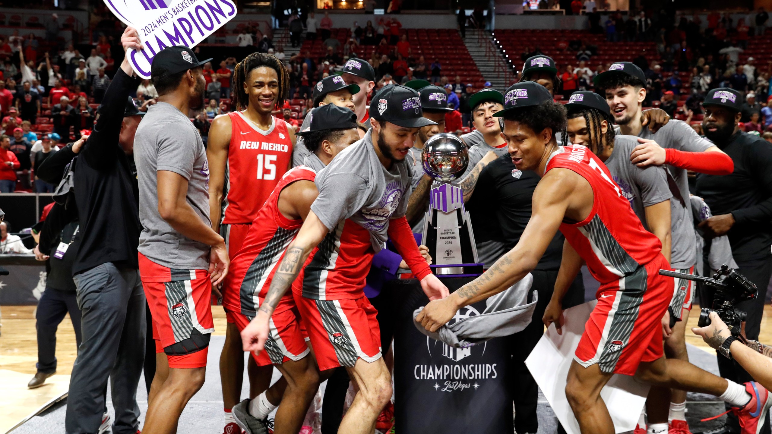New Mexico players celebrate after defeating San Diego State in an an NCAA college basketball championship game at the Mountain West Conference tournament Saturday, March 16, 2024, in Las Vegas. New Mexico guards Jaelen House, center left, and Tru Washington, center right, dance in front of the trophy. (AP Photo/Steve Marcus)