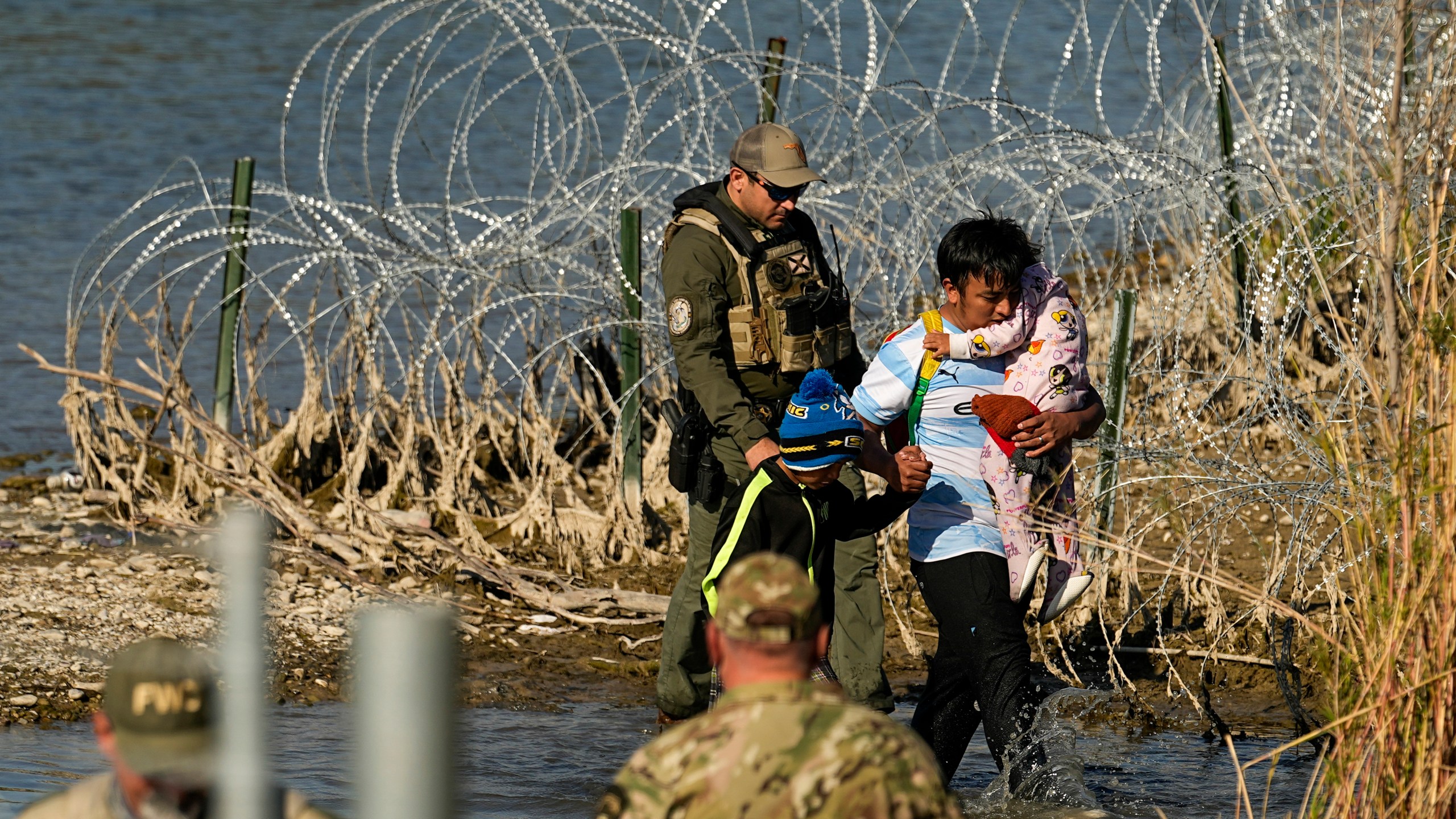FILE - Migrants are taken into custody by officials at the Texas-Mexico border, Jan. 3, 2024, in Eagle Pass, Texas. The Supreme Court on Tuesday, March 12, 2024 extended a stay on a new Texas law that would empower police to arrest migrants suspected of illegally crossing the U.S.-Mexico border. The order puts the law on hold until at least Monday while the high court considers a challenge by the Justice Department, which has called the law an unconstitutional overreach. (AP Photo/Eric Gay, file)