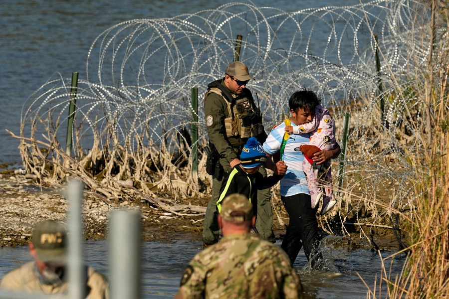 FILE - Migrants are taken into custody by officials at the Texas-Mexico border, Jan. 3, 2024, in Eagle Pass, Texas. The Supreme Court on Tuesday, March 12, 2024 extended a stay on a new Texas law that would empower police to arrest migrants suspected of illegally crossing the U.S.-Mexico border. The order puts the law on hold until at least Monday while the high court considers a challenge by the Justice Department, which has called the law an unconstitutional overreach. (AP Photo/Eric Gay, file)