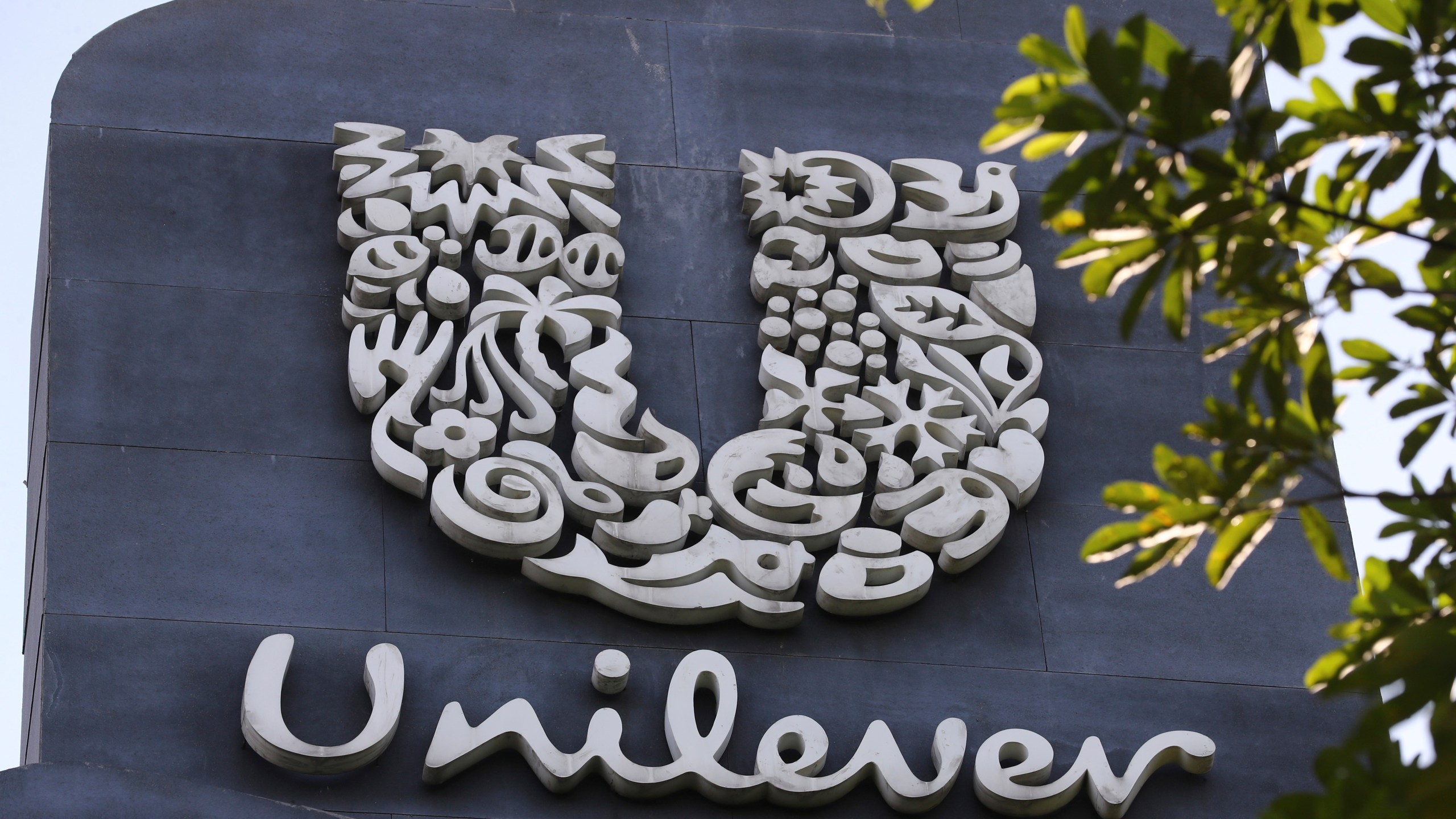 FILE - A Unilever logo is displayed outside the head office of PT Unilever Indonesia Tbk. in Tangerang, Indonesia, Tuesday, Nov. 16, 2021. Unilever, the company that makes Ben & Jerry’s ice cream, Dove soaps and Vaseline, says it's cutting 7,500 jobs and spinning off its ice cream business to reduce costs and boost profits. (AP Photo/Tatan Syuflana, File)