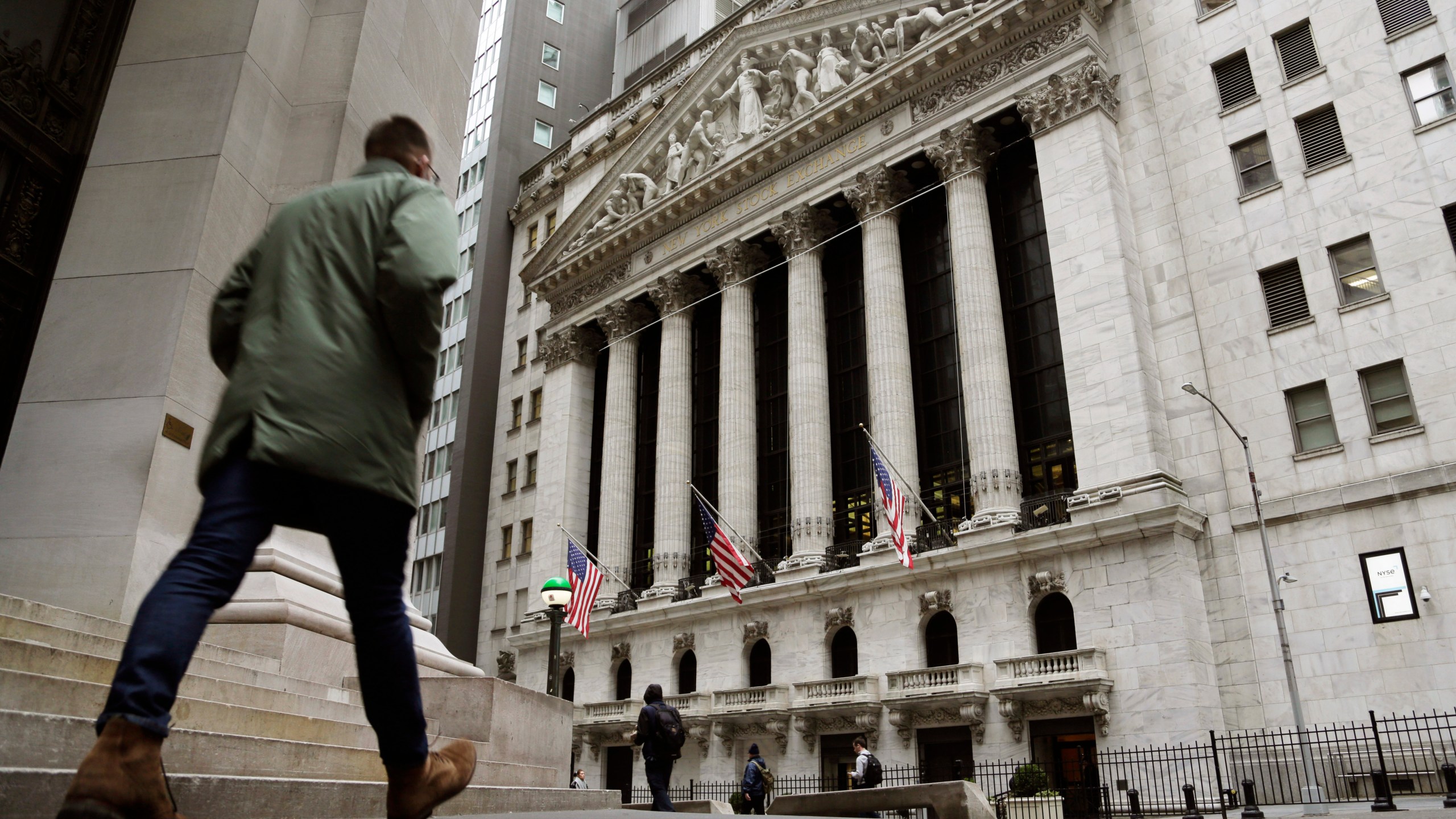 FILE — People pass the front of the New York Stock Exchange, March 22, 2023. The average Wall Street bonus fell slightly last year to $176,500 as firms took a “more cautious approach” to compensation, New York state’s comptroller reported Tuesday, March 19, 2024. (AP Photo/Peter Morgan, File)