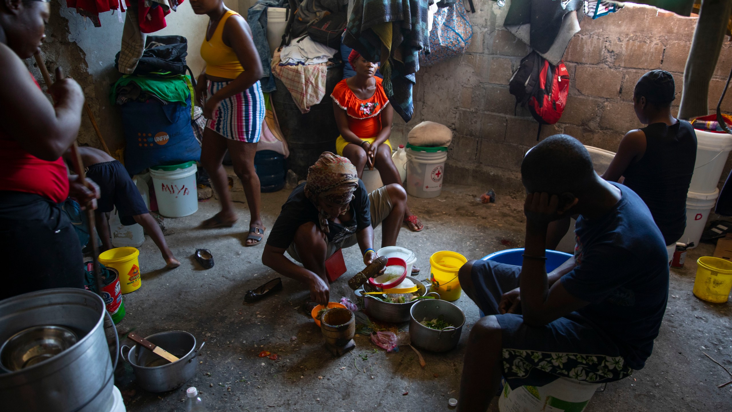 FILE - A woman prepares food at a shelter for families displaced by gang violence in Port-au-Prince, Haiti, Dec. 9, 2021. Catastrophic hunger is so dire in two world hotspots that famine is imminent in northern Gaza and approaching in Haiti, with hundreds of thousands of people in both places struggling to avoid starvation, according to international food security experts and aid groups. (AP Photo/Odelyn Joseph, File)