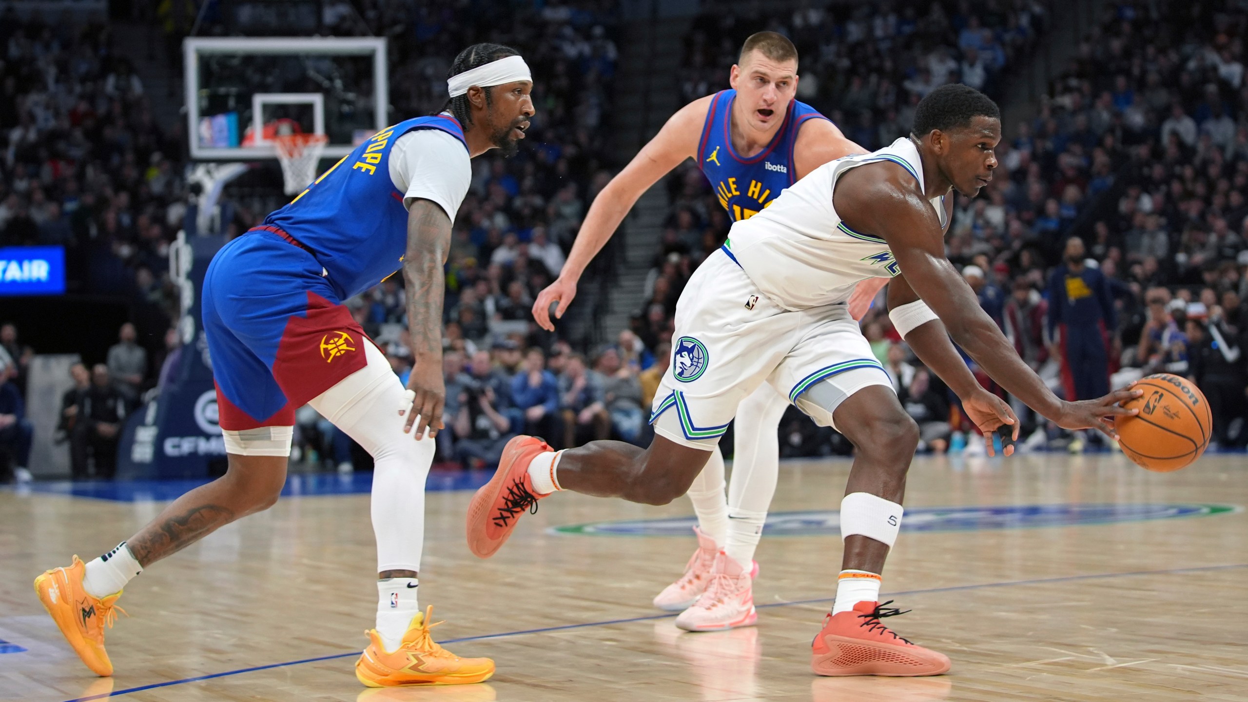Minnesota Timberwolves guard Anthony Edwards, front right, works toward the basket as Denver Nuggets guard Kentavious Caldwell-Pope, left, and center Nikola Jokic defend during the first half of an NBA basketball game Tuesday, March 19, 2024, in Minneapolis. (AP Photo/Abbie Parr)