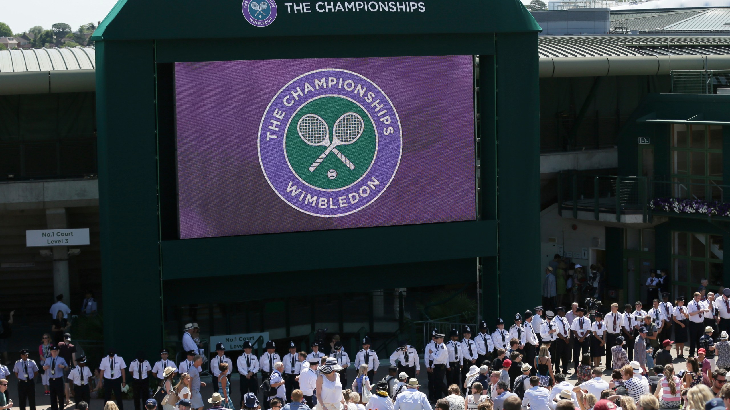 FILE - British police officers line up under the big screen on Murray Mount, ahead of the minute silence for the victims of the shooting in Tunisia last week, at the All England Lawn Tennis Championships in Wimbledon, London, Friday July 3, 2015. Tennis could be on the verge of massive structural change if separate proposals formulated by the four Grand Slam tournaments and the WTA and ATP professional tours can succeed. (AP Photo/Tim Ireland, File)