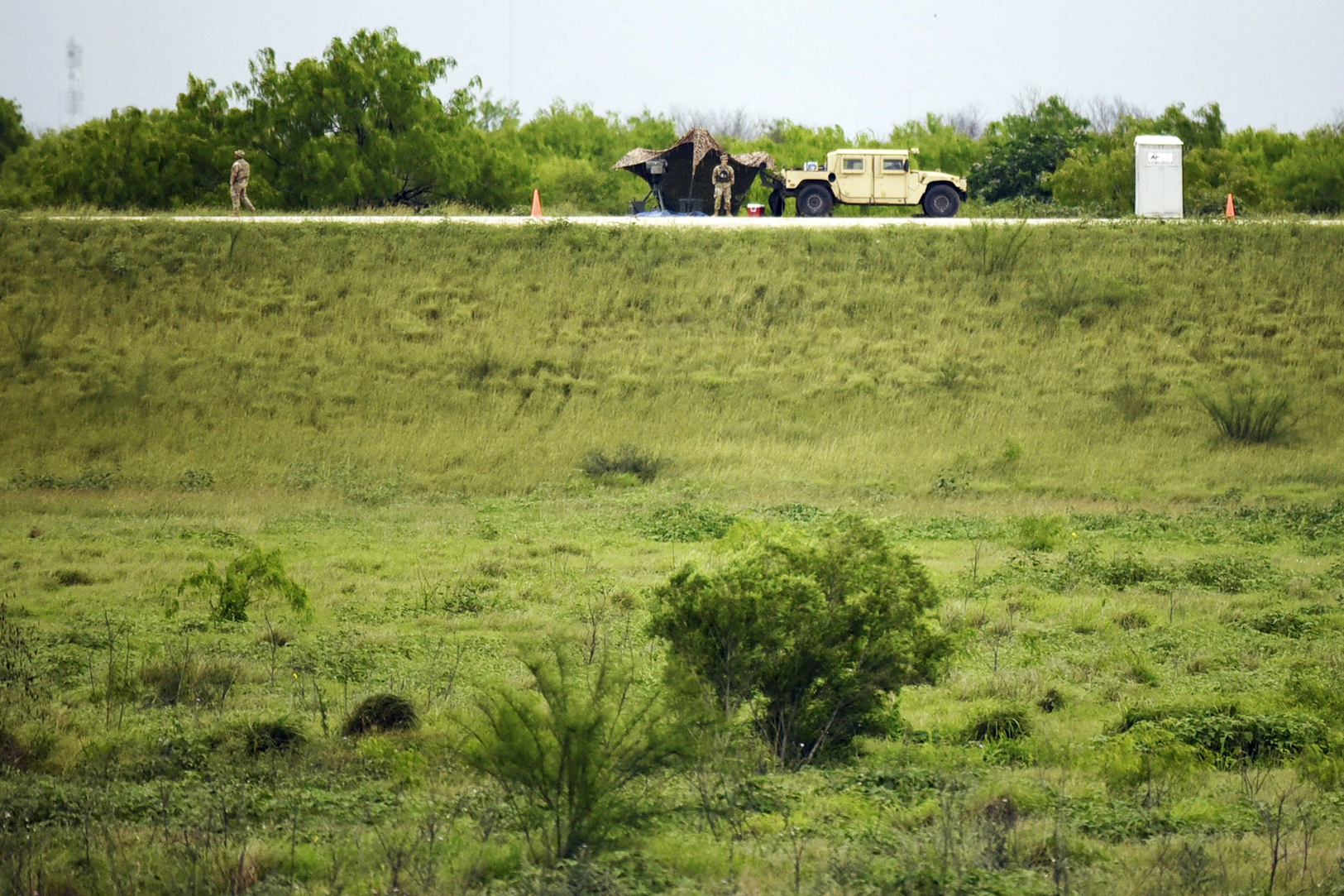 Two members of the National Guard patrol an area of land behind the federal border wall Tuesday evening, March 19, 2024, in Mission, Texas. A divided Supreme Court on Tuesday allowed Texas to begin enforcing a law that gives police broad powers to arrest migrants suspected of crossing the border illegally while a legal battle over the measure plays out. (AP Photo/Valerie Gonzalez)