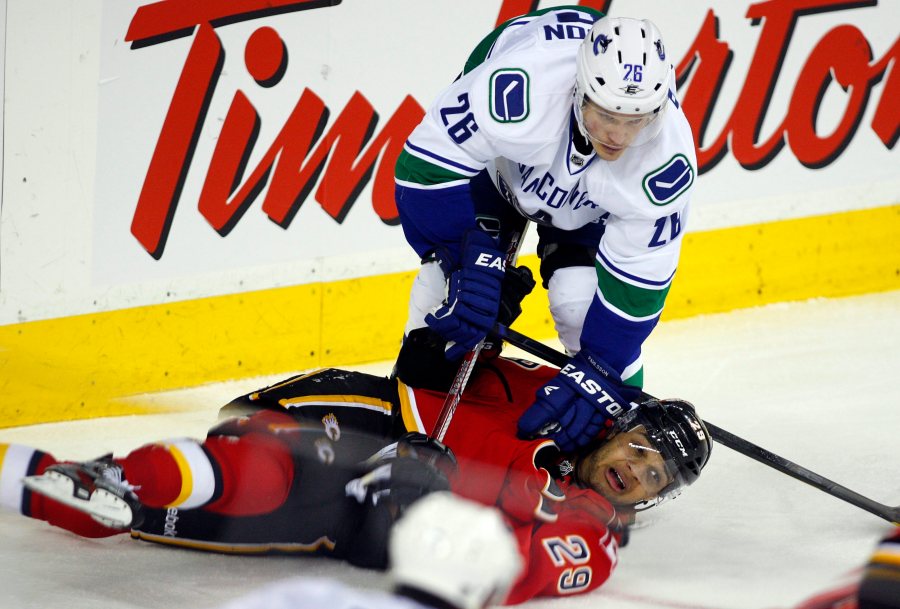 FILE - Vancouver Canucks' Samuel Pahlsson, top, of Sweden, holds down Calgary Flames' Akim Aliu, of Nigeria, during the third period of an NHL hockey game in Calgary, Alberta, Thursday, April 5, 2012. After years of feeling alienated by the NHL and campaigning to diversify the sport, Akim Aliu is getting one more shot at playing pro hockey, this time with the San Jose Sharks minor-league affiliate. Sharks general manager Mike Grier informed reporters at the league’s GM meetings in Florida on Wednesday, March 20, 2024, that he offered Aliu a tryout contract with the American Hockey League San Jose Barracuda for the remainder of the season.(AP Photo/The Canadian Press, Jeff McIntosh, File)