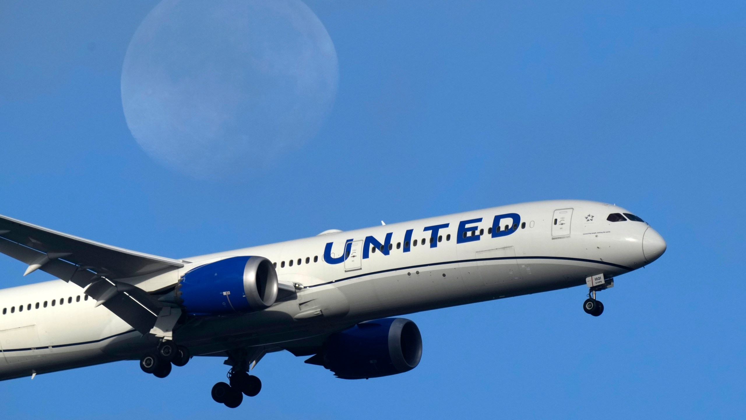 FILE - A United Airlines Boeing 787 approaches for landing in Lisbon, Sept. 2, 2023, with the setting moon in the background. Don't have enough airline miles for that free flight? United Airlines is now letting people pool and share their frequent-flyer points with family and friends, the airline announced Thursday, March 21, 2024. (AP Photo/Armando Franca, File)