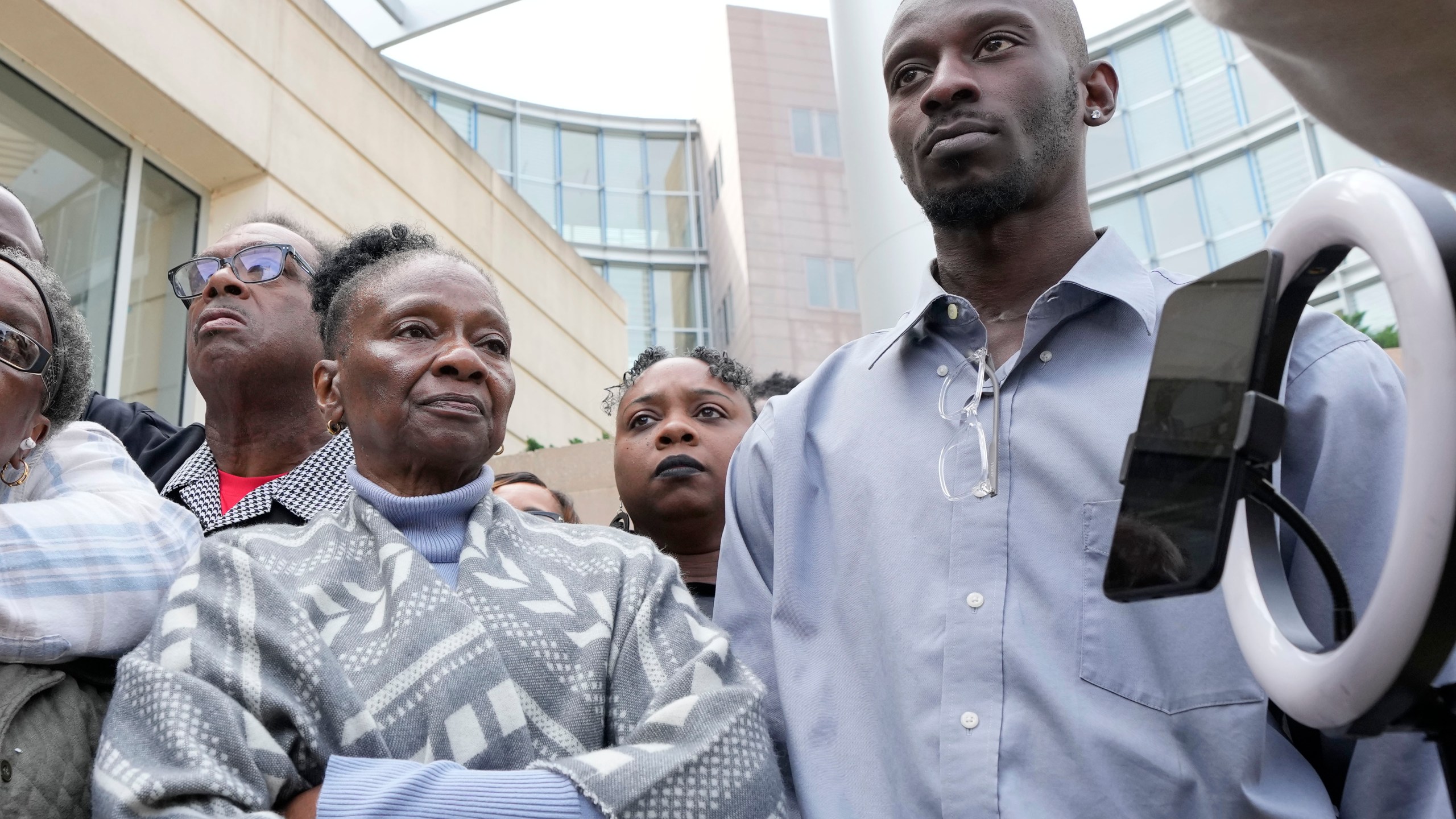 Mary Jenkins and her son Michael Corey Jenkins, right, listen as civil co-counsel Malik Shabazz, left, speaks with reporters outside the federal courthouse in Jackson, Miss., Thursday, March 21, 2024, following the sentencing of former Rankin County deputy Brett McAlpin to more than 27 years in federal prison for his role in the racially motivated, violent torture of Michael Corey Parker and his friend Eddie Terrell Jenkins last year. McAlpin is the fifth of six former Mississippi Rankin County law enforcement officers to be sentenced in federal court since Tuesday. (AP Photo/Rogelio V. Solis)