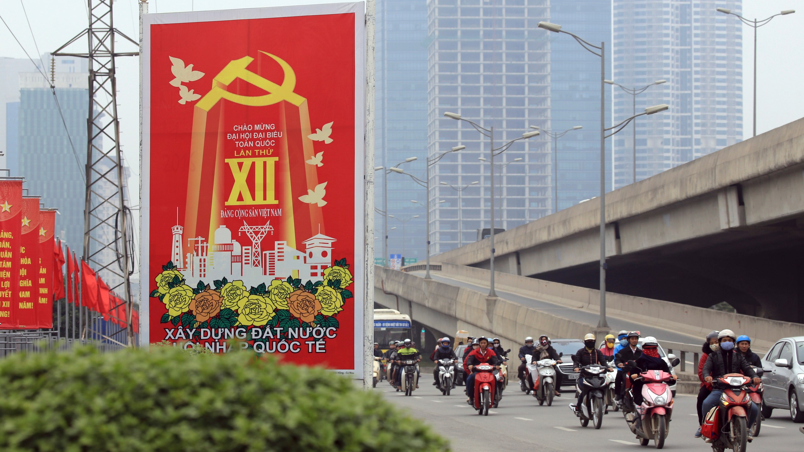 FILE - Traffic ride past a Communist party poster in Hanoi, Vietnam on Jan. 19, 2016. Vietnam's president has resigned as the ruling communist party in the latest episode of a “blazing furnace” anti-corruption campaign. Vo Van Thuong was the second to resign from the post in just over a year. The presidency is largely a ceremonial role. The most powerful job is held by Communist Party general secretary Nguyen Phu Trong. (AP Photo/Hau Dinh, File)