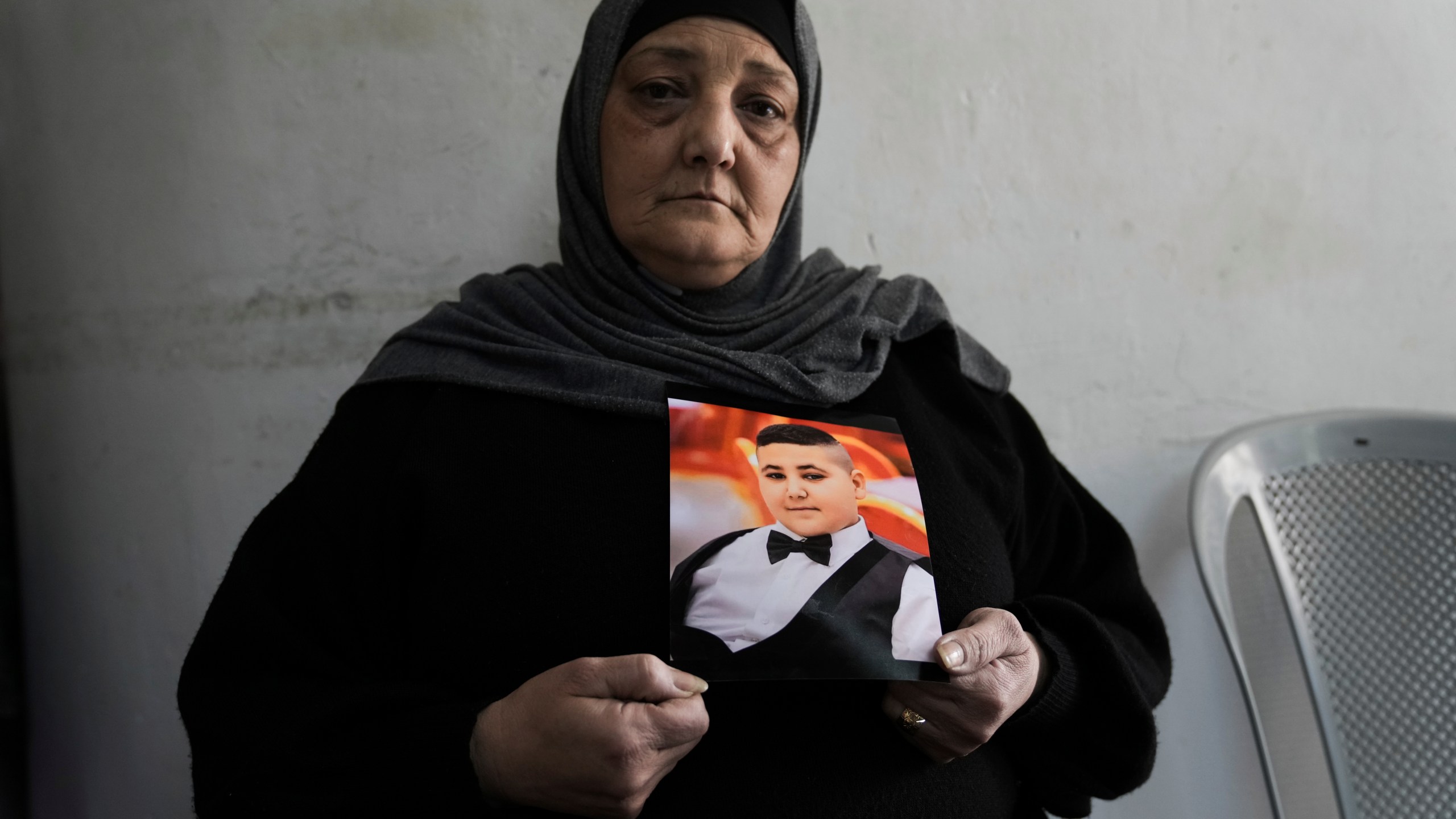 Rawiya Halhouli holds a photo of her slain son Rami Halhouli, in their house in Shuafat refugee camp in east Jerusalem, Sunday, March 17, 2024. Halhouli, 12, was fatally by an Israeli police officer while launching a firework on March 12. (AP Photo/Mahmoud Illean)