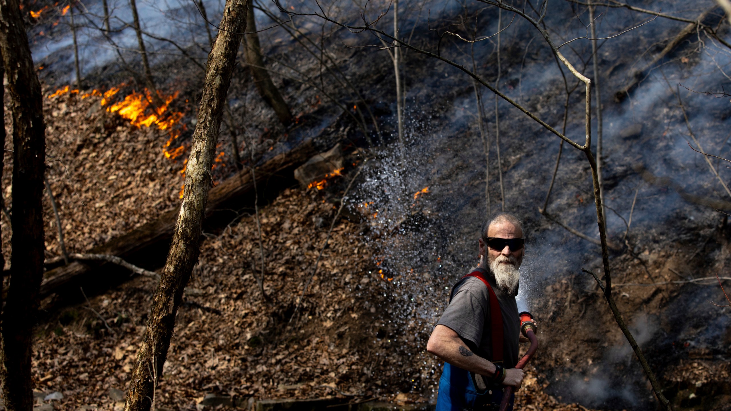 Bergton Volunteer Fire Company firefighter James Morris sprays water on a wildfire as it approaches a house on Brushy Run Road, Wednesday, March 20, 2024, in Bergton, Va. (Daniel Lin/Daily News-Record via AP)