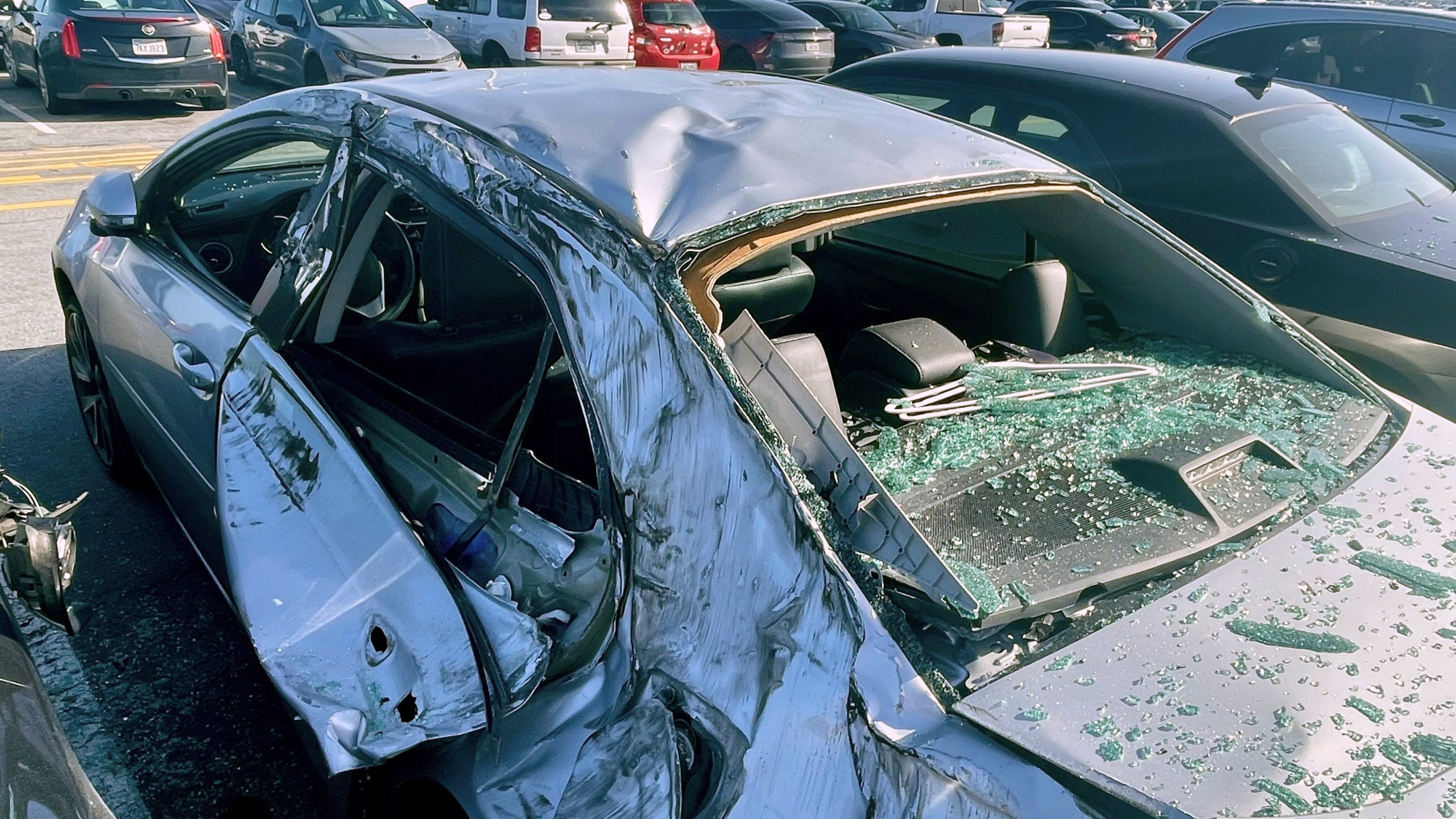 FILE - A damaged car is seen in a airport parking lot after debris from tire which fell from a Boeing 777 landed on it at San Francisco International Airport, March 7, 2024. Cracked windshields on jetliners and engine problems that cause flight delays don't normally attract much attention, but routine and rare problems with passenger planes are attracting an unusual amount of news coverage. (AP Photo/Haven Daley, File)