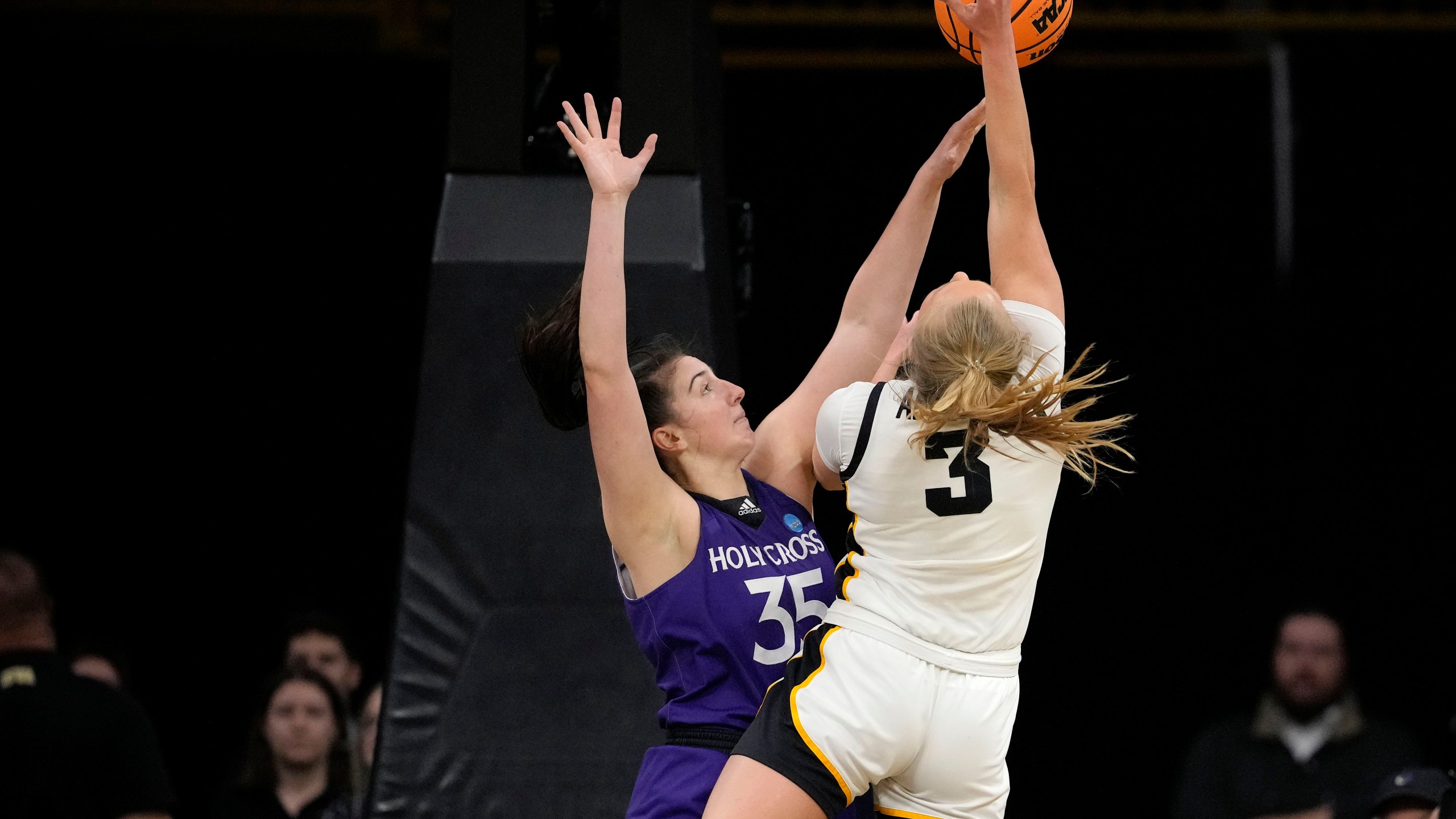 Iowa guard Sydney Affolter (3) shoots a basket as she is fouled by Holy Cross forward Lindsay Berger (35) in the first half of a first-round college basketball game in the NCAA Tournament, Saturday, March 23, 2024, in Iowa City, Iowa. (AP Photo/Matthew Putney)