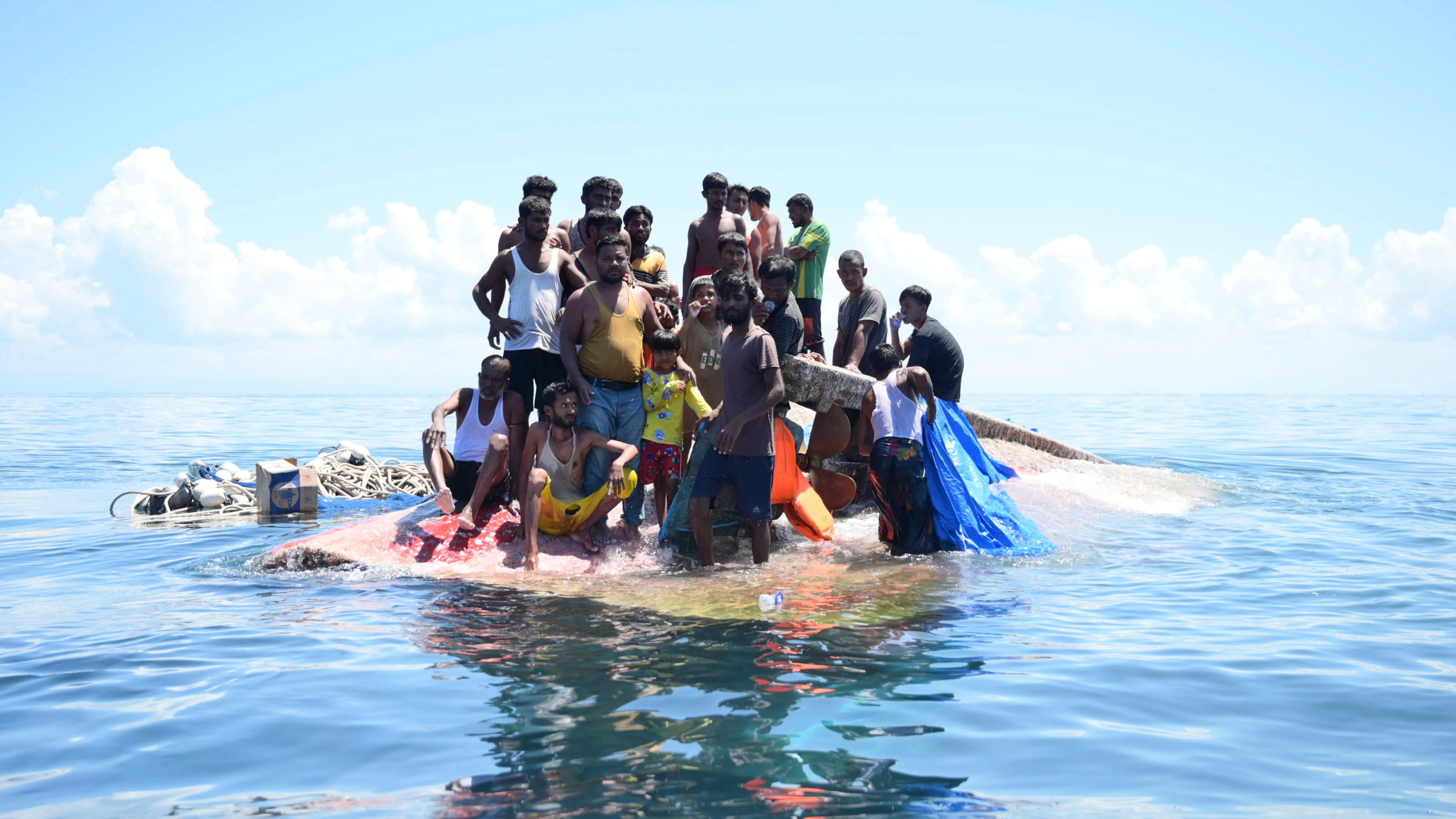Rohingya refugees stand on their capsized boat before being rescued in the waters off West Aceh, Indonesia, Thursday, March 21, 2024. The wooden boat carrying dozens of Rohingya Muslims capsized off Indonesia's northernmost coast on Wednesday, according to local fishermen. (AP Photo/Reza Saifullah)
