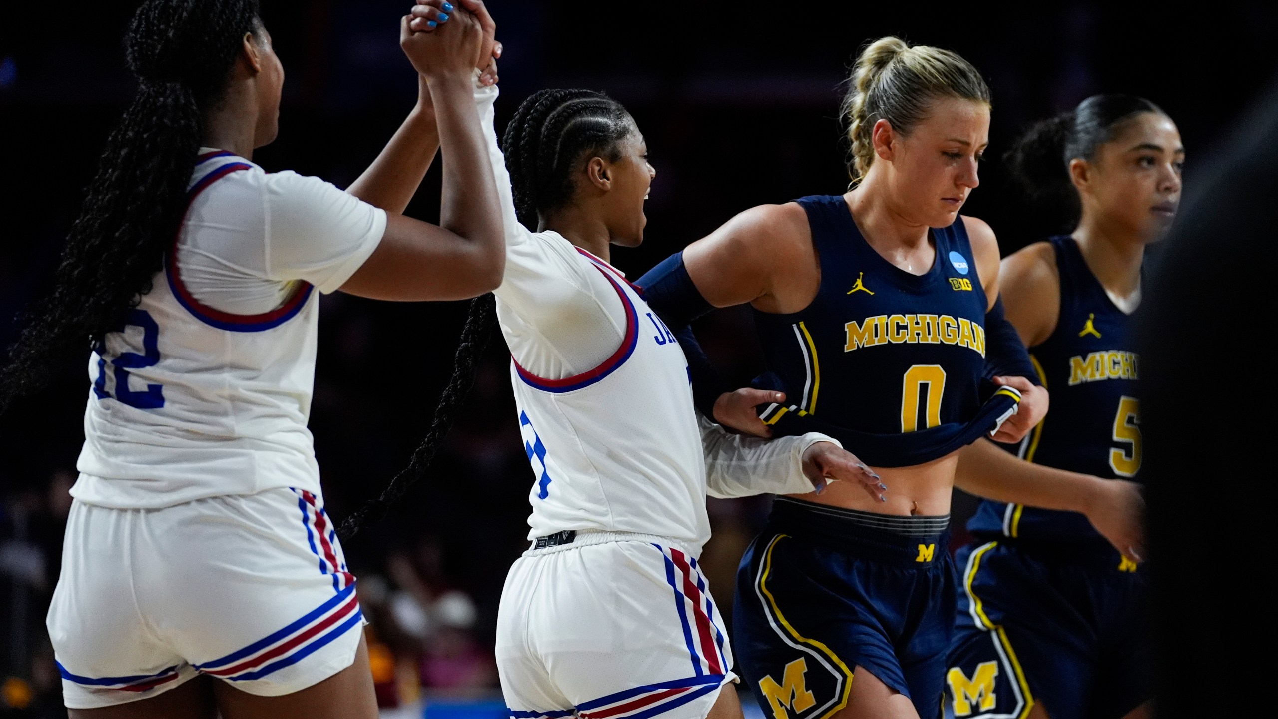 Kansas guard Wyvette Mayberry, center, celebrates with guard S'Mya Nichols (12) after winning 81-72 over Michigan in overtime of a first-round college basketball game in the women's NCAA Tournament in Los Angeles, Saturday, March 23, 2024. Michigan guard Elissa Brett (0) and guard Laila Phelia (5) react. (AP Photo/Ashley Landis)