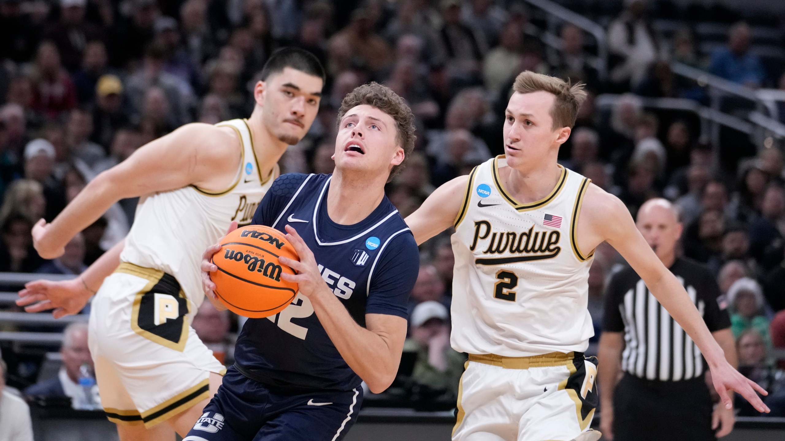Utah State's Mason Falslev (12) heads to the basket past Purdue's Zach Edey and Fletcher Loyer (2) during the first half of a second-round college basketball game in the NCAA Tournament, Sunday, March 24, 2024 in Indianapolis. (AP Photo/Michael Conroy)
