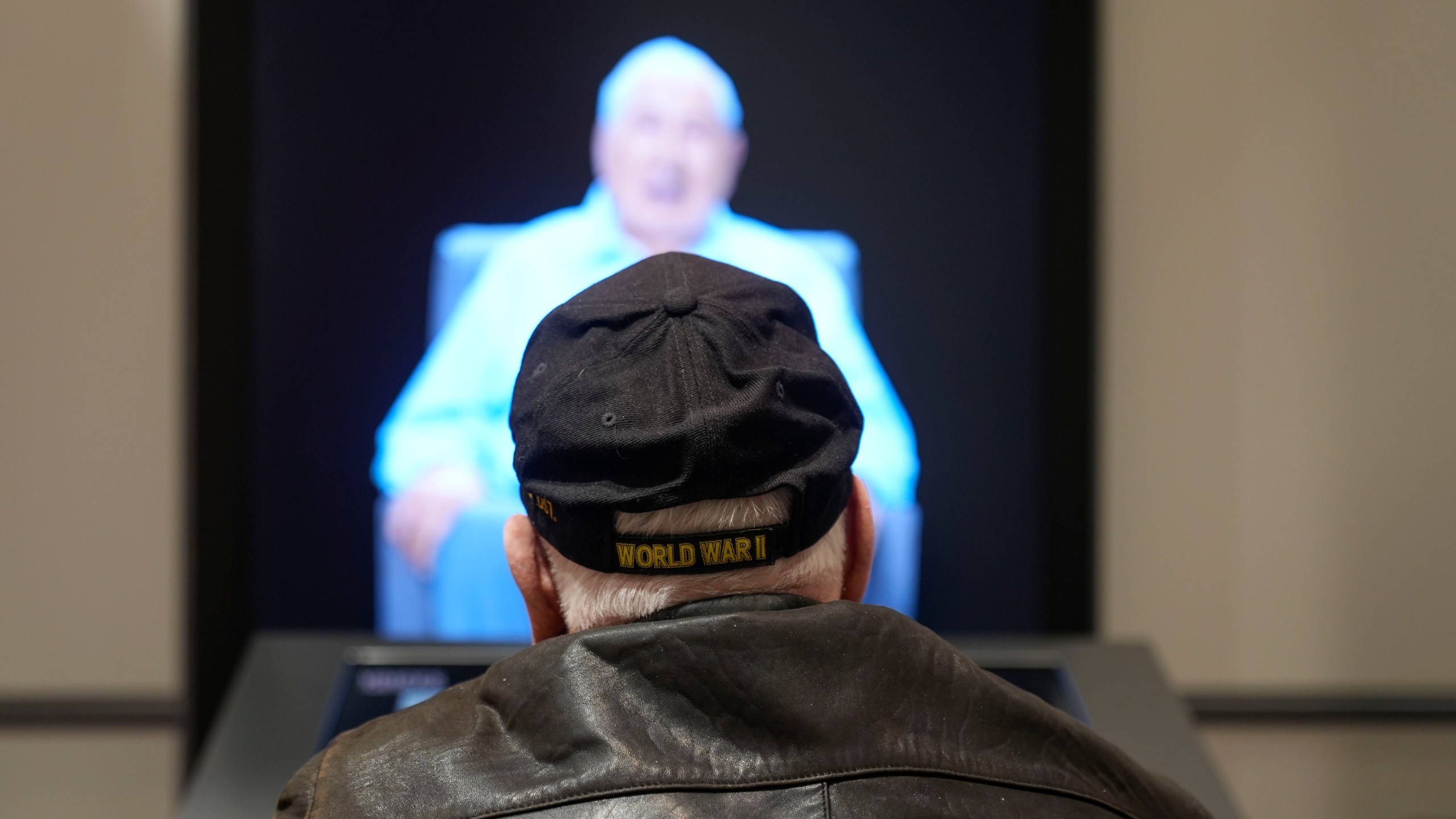World War II veteran Olin Pickens, of Nesbit, Miss., who served in the U.S. Army 805th Tank Destroyer Battalion, looks at the virtual exhibit of himself at the National World War II Museum in New Orleans, Wednesday, March 20, 2024. An interactive exhibit opening Wednesday at the museum will use artificial intelligence to let visitors hold virtual conversations with images of veterans, including a Medal of Honor winner who died in 2022. (AP Photo/Gerald Herbert)