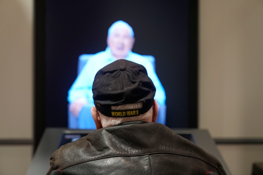 World War II veteran Olin Pickens, of Nesbit, Miss., who served in the U.S. Army 805th Tank Destroyer Battalion, looks at the virtual exhibit of himself at the National World War II Museum in New Orleans, Wednesday, March 20, 2024. An interactive exhibit opening Wednesday at the museum will use artificial intelligence to let visitors hold virtual conversations with images of veterans, including a Medal of Honor winner who died in 2022. (AP Photo/Gerald Herbert)