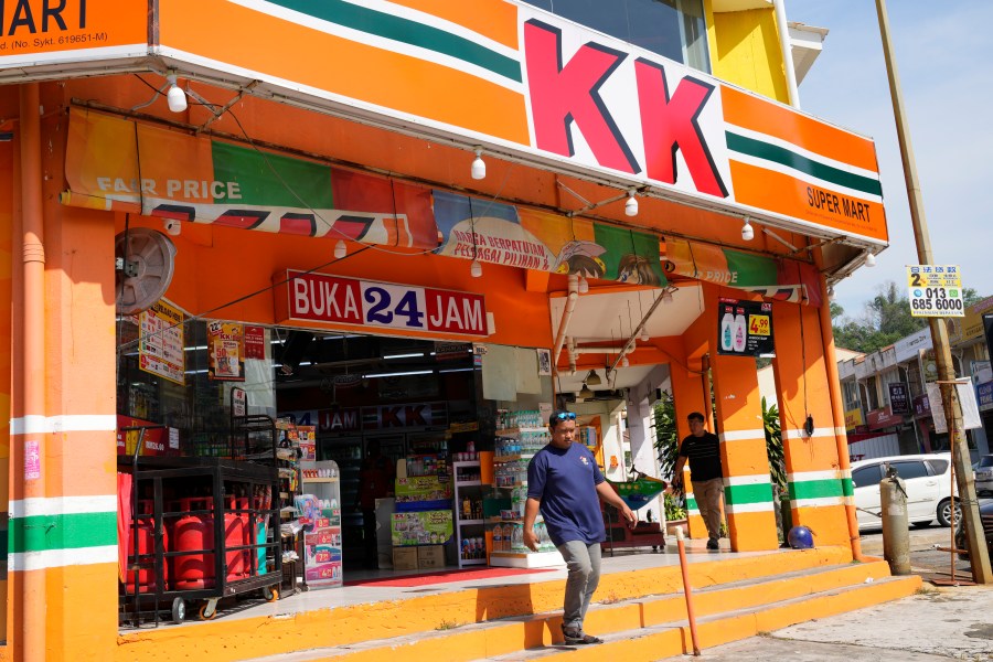 A customer walk out from KK Mart convenience store in Puchong area on the outskirts of of Kuala Lumpur, Malaysia, Tuesday, March 26, 2024. The owner of a Malaysian convenience store chain was charged Tuesday with deliberately wounding the religious feelings of others after socks with the word "Allah" were found sold in some outlets. (AP Photo/Vincent Thian)