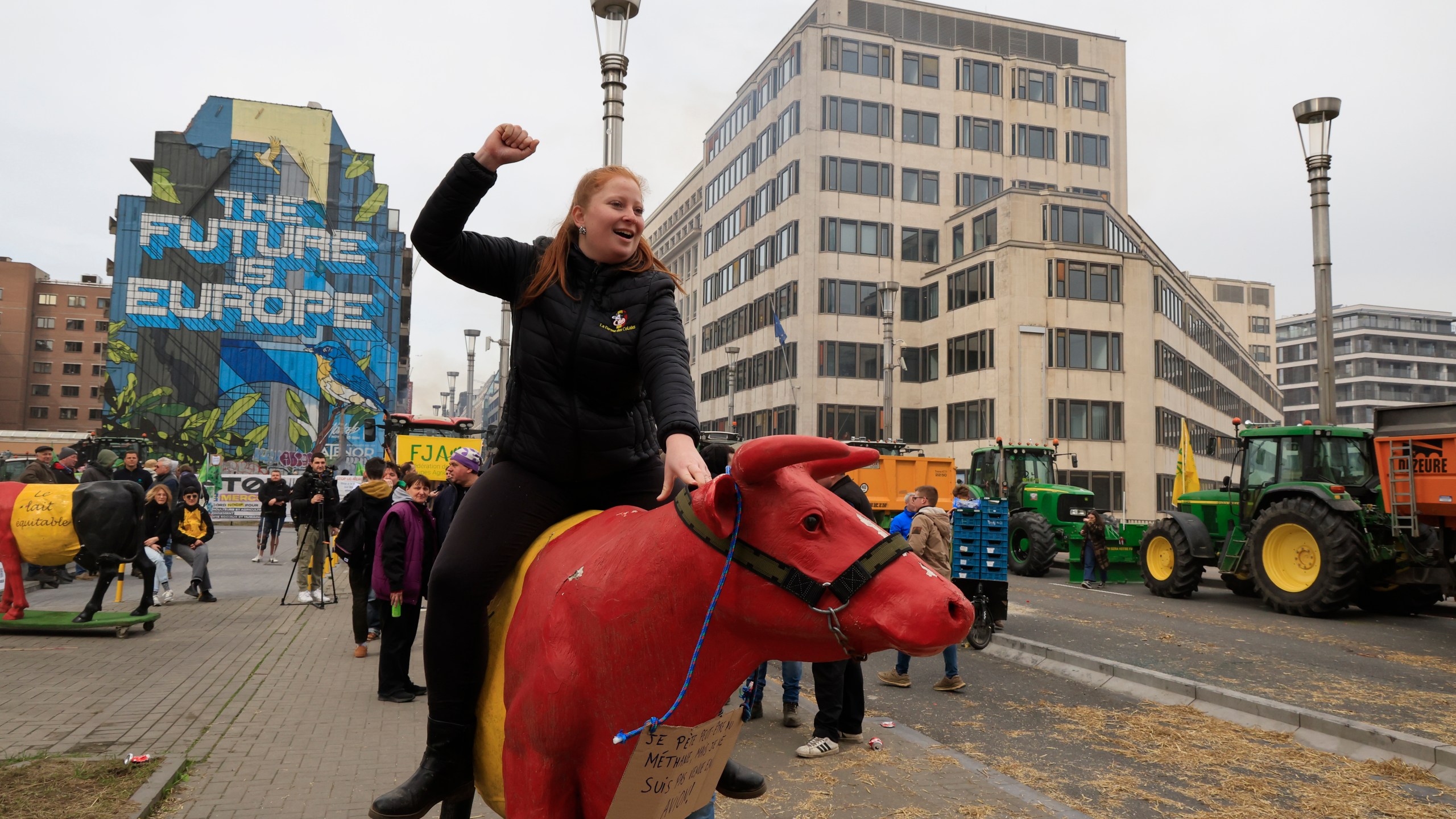A protestor rides a plastic cow during a demonstration of farmers near the European Council building in Brussels, Tuesday, March 26, 2024. Dozens of tractors sealed off streets close to European Union headquarters where the 27 EU farm ministers are meeting to discuss the crisis in the sector which has led to months of demonstrations across the bloc. (AP Photo/Geert Vanden Wijngaert)