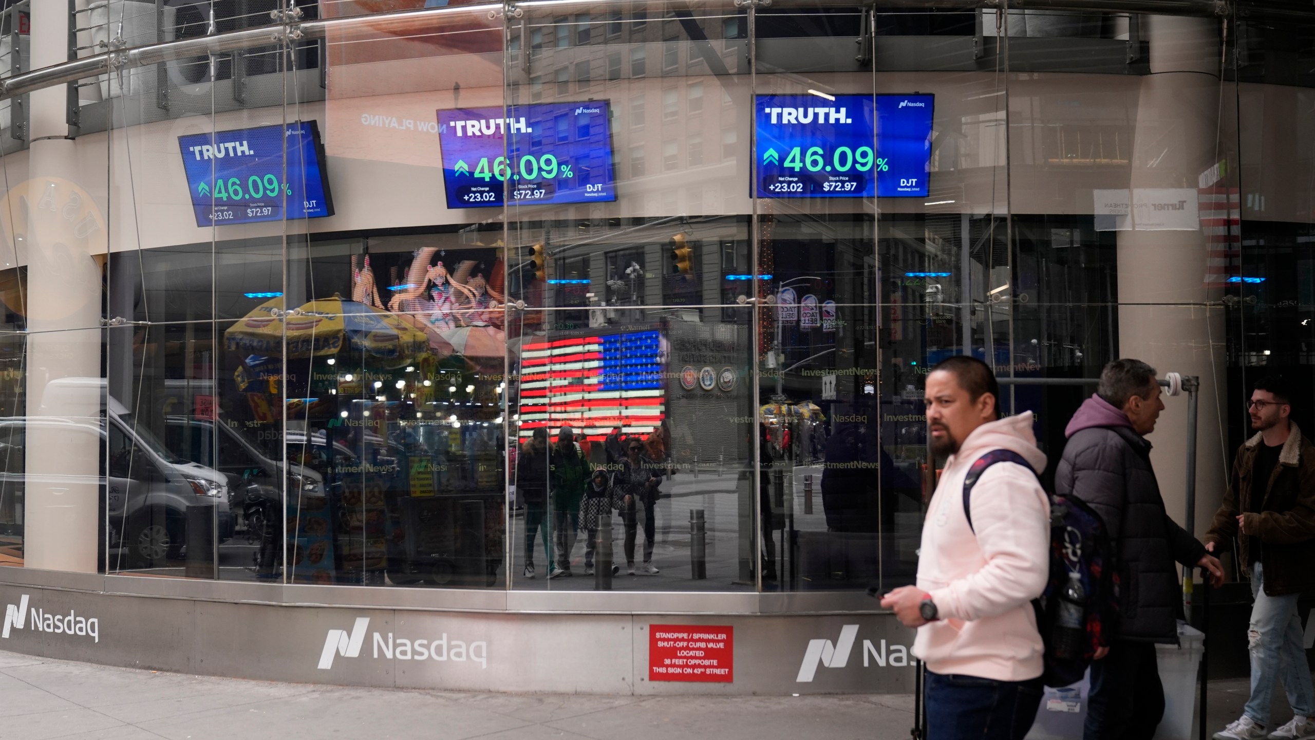 Pedestrians walk past the Nasdaq building Tuesday, March 26, 2024, in New York. Trump Media, which runs the social media platform Truth Social, now takes Digital World's place on the Nasdaq stock exchange. (AP Photo/Frank Franklin II)