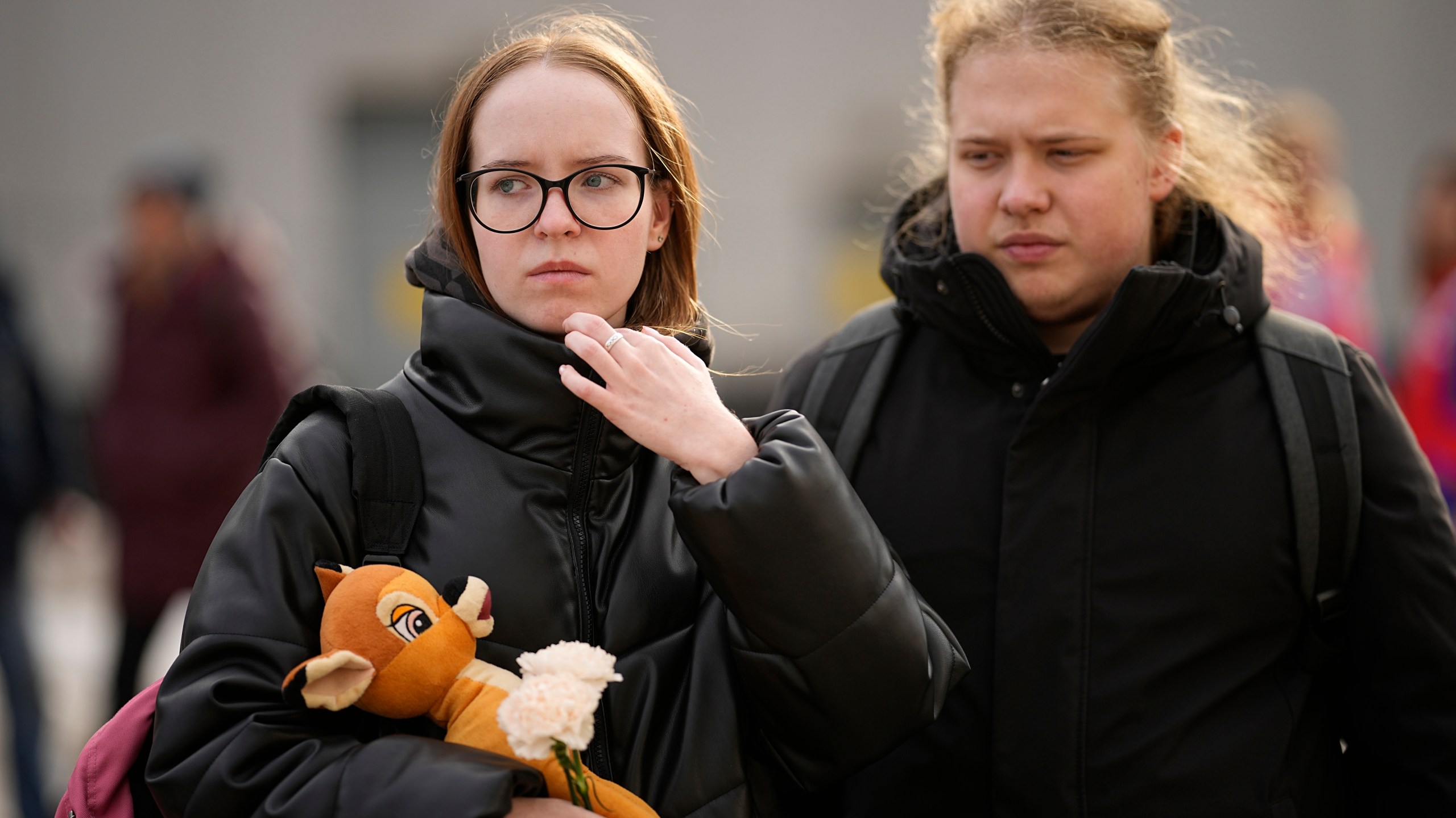 A woman carries flower and a toy to place them at a makeshift memorial in front of the Crocus City Hall on the western outskirts of Moscow, Russia, Tuesday, March 26, 2024. Russian state news agency Tass says 22 victims of the concert hall attack that killed more than 130 people remain in serious condition in the hospital. (AP Photo/Alexander Zemlianichenko)