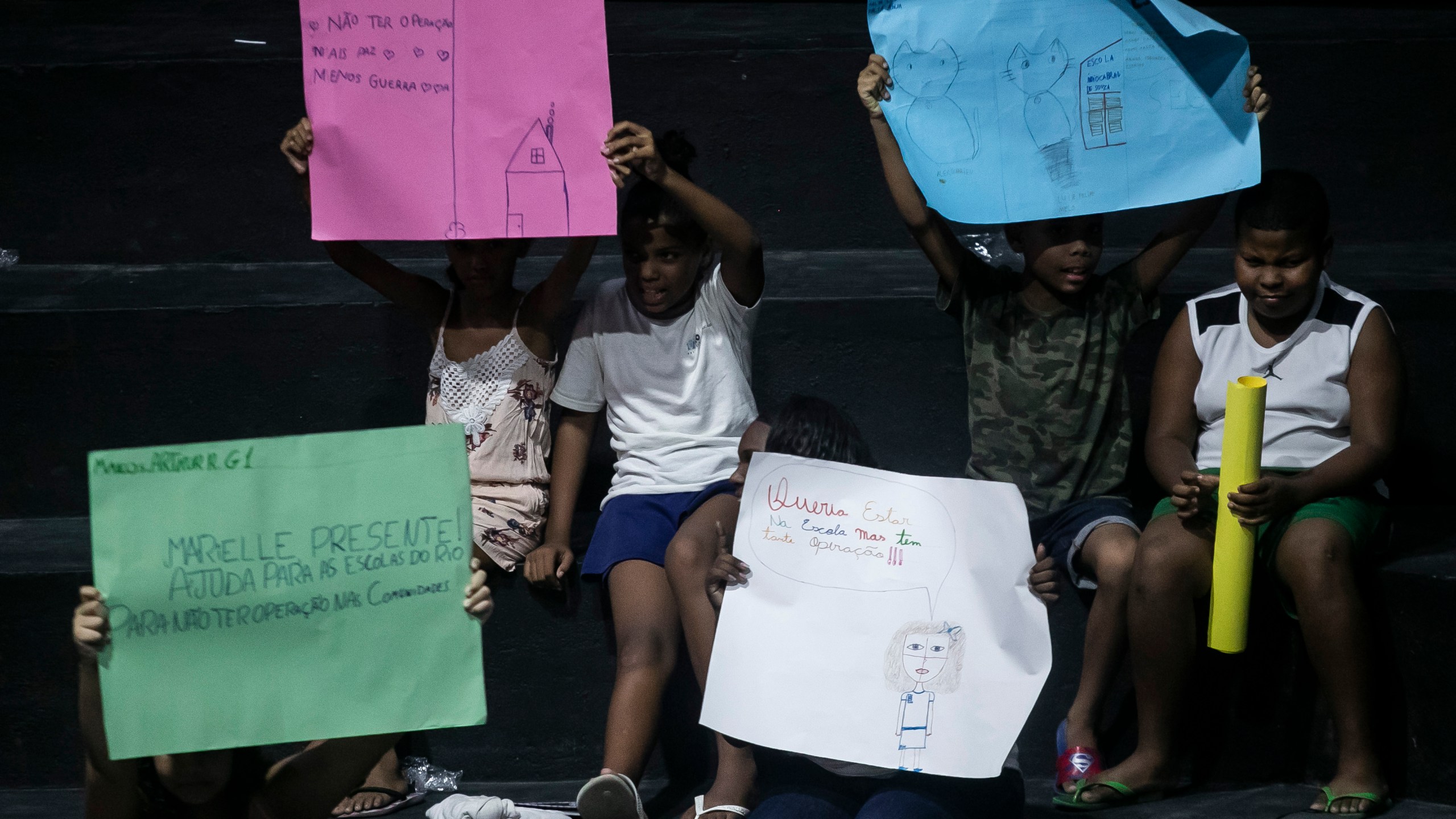 Children hold drawings that represent their experiences of living in the Mare favela during the launch of the book titled “I was supposed to be at school” in the Mare favela of Rio de Janeiro, Brazil, Monday, March 25, 2024. Dozens of kids and teenagers from one of Rio de Janeiro's most violent favelas gathered on Monday to celebrate their most important piece of work yet: a book that aims to show authorities how they see police violence in their Maré community from a young age. (AP Photo/Bruna Prado)