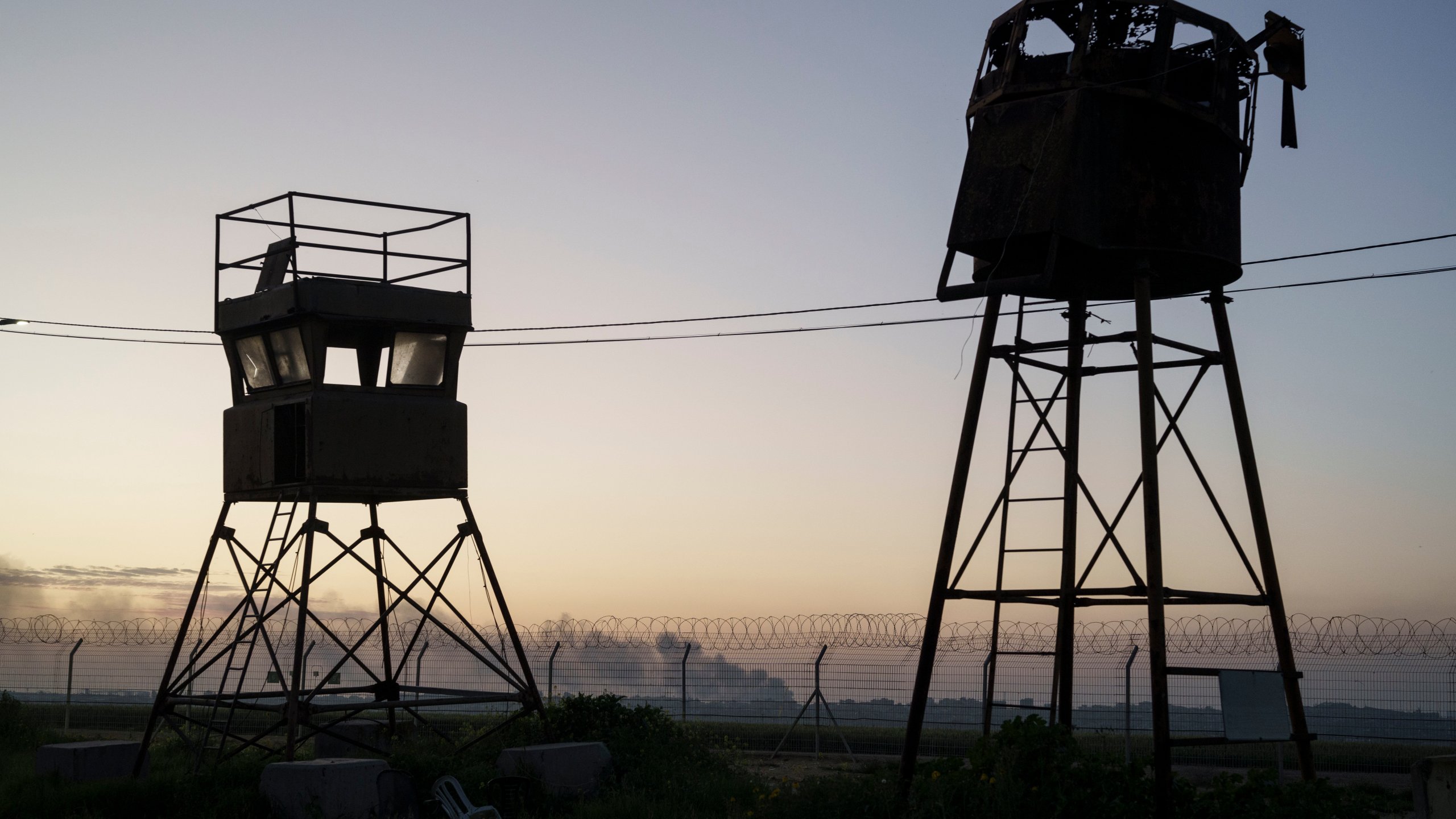 Old observation towers stand near a fence as smoke rises after an explosion in the Gaza Strip, seen from Kibbutz Nahal Oz, Israel, Wednesday, Feb. 28, 2024. (AP Photo/Leo Correa)