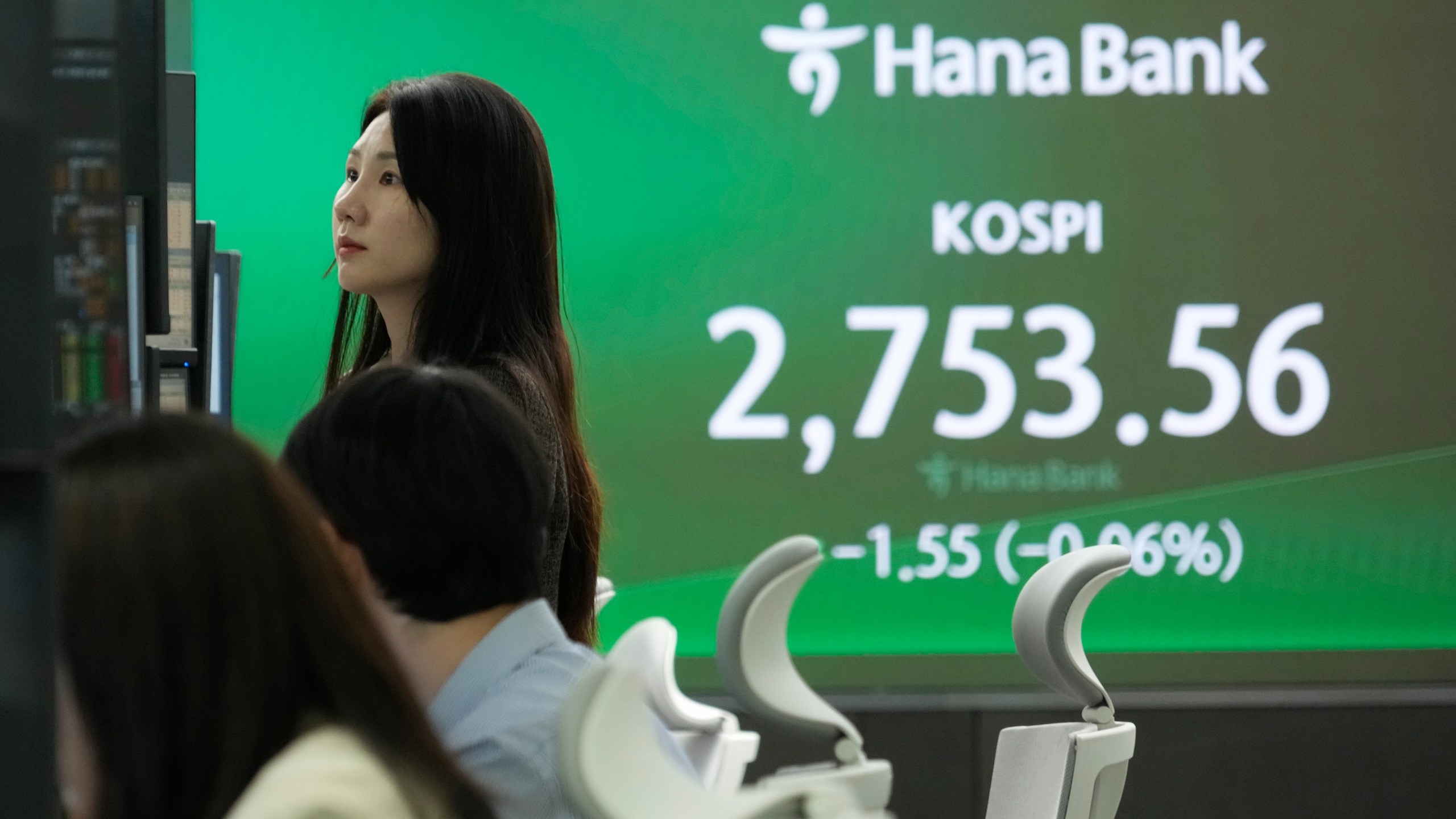 A currency trader watches monitors near a screen showing the Korea Composite Stock Price Index (KOSPI) at the foreign exchange dealing room of the KEB Hana Bank headquarters in Seoul, South Korea, Thursday, March 28, 2024. Asian shares were mixed on Thursday after U.S. stocks broke out of a three-day lull to close at a record. (AP Photo/Ahn Young-joon)