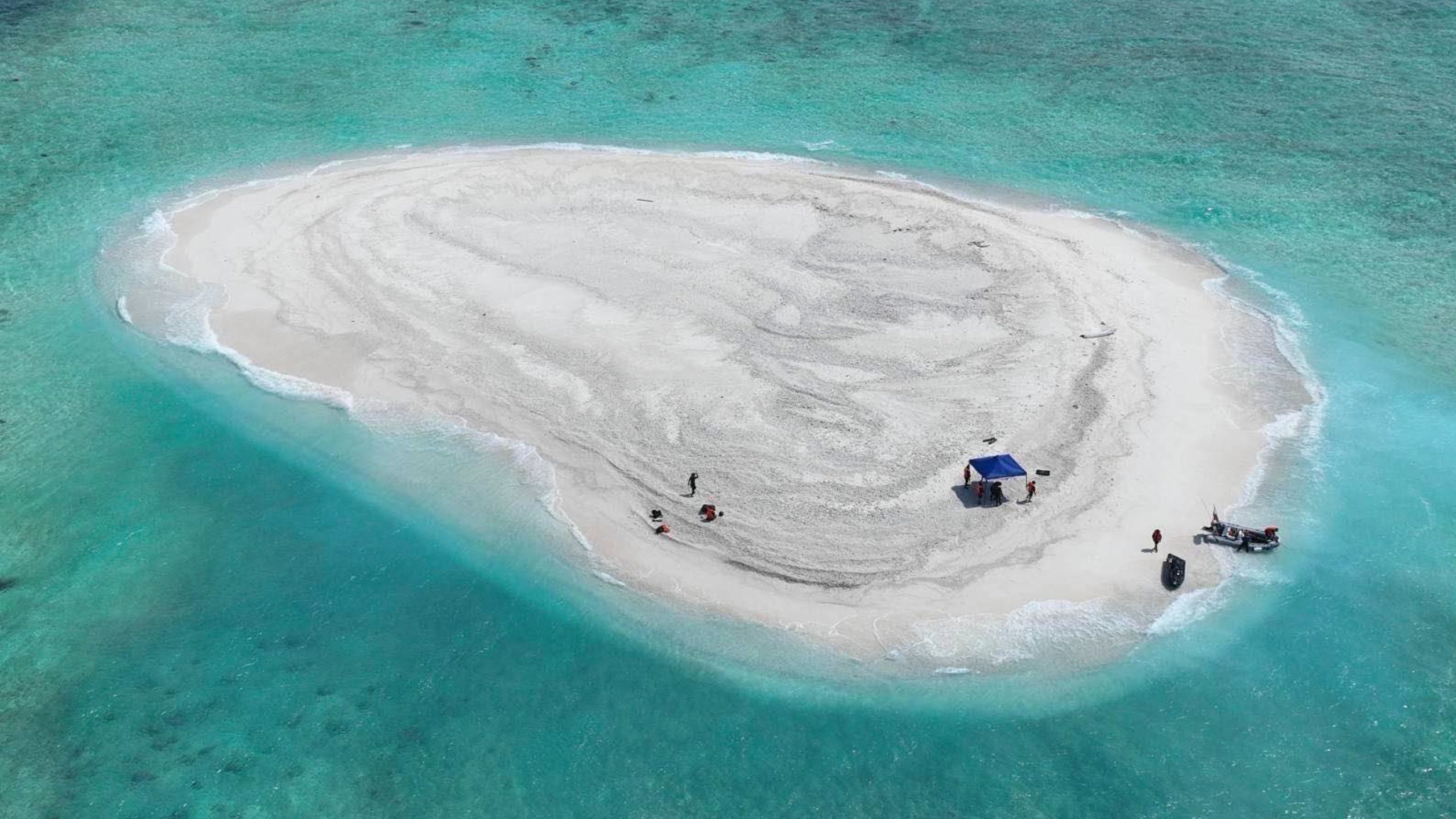 In this photo provided by the Philippine Coast Guard, Filipino scientists reach sandbars called Sandy Cay at the disputed South China Sea on Thursday March 21, 2024. Chinese coast guard ships, backed by a military helicopter, tried to dangerously block but failed to stop two Philippine government vessels carrying scientists from reaching two barren sandbars called Sandy Cay in the disputed South China Sea, Philippine officials said Friday. (Philippine Coast Guard via AP)