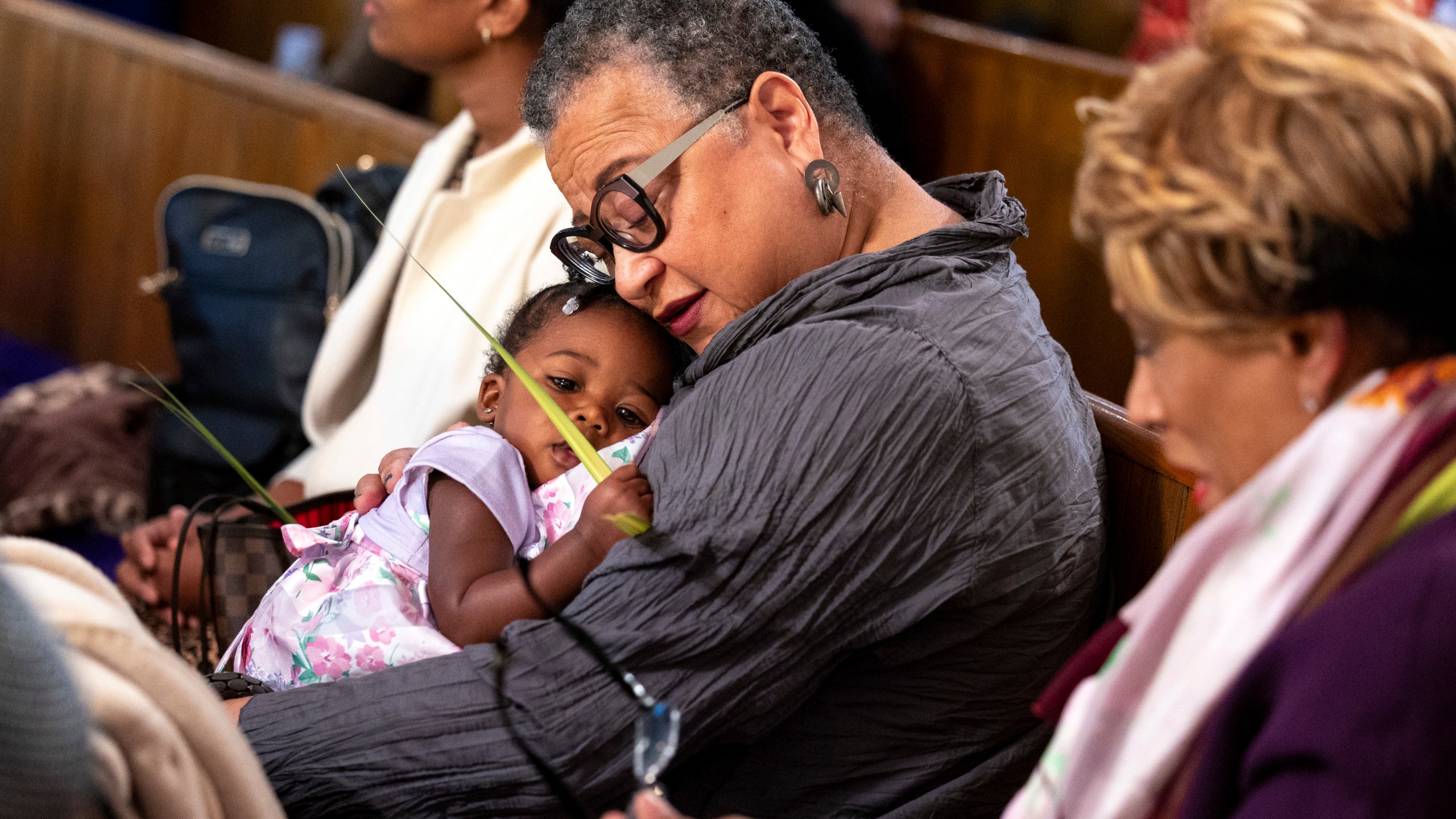 Marie Johns holds her her one-year-old daughter during Palm Sunday services at the Metropolitan AME Church in Washington, Sunday, March 24, 2024. Rev. William Lamar IV at Washington, D.C.’s historic Metropolitan AME has adjusted to offering both virtual and in-person services since the COVID-19 pandemic. After a noticeable attendance drop, more Metropolitan congregants are choosing in-person worship over virtual, even as they mourn members who died from COVID-19. (AP Photo/Amanda Andrade-Rhoades)