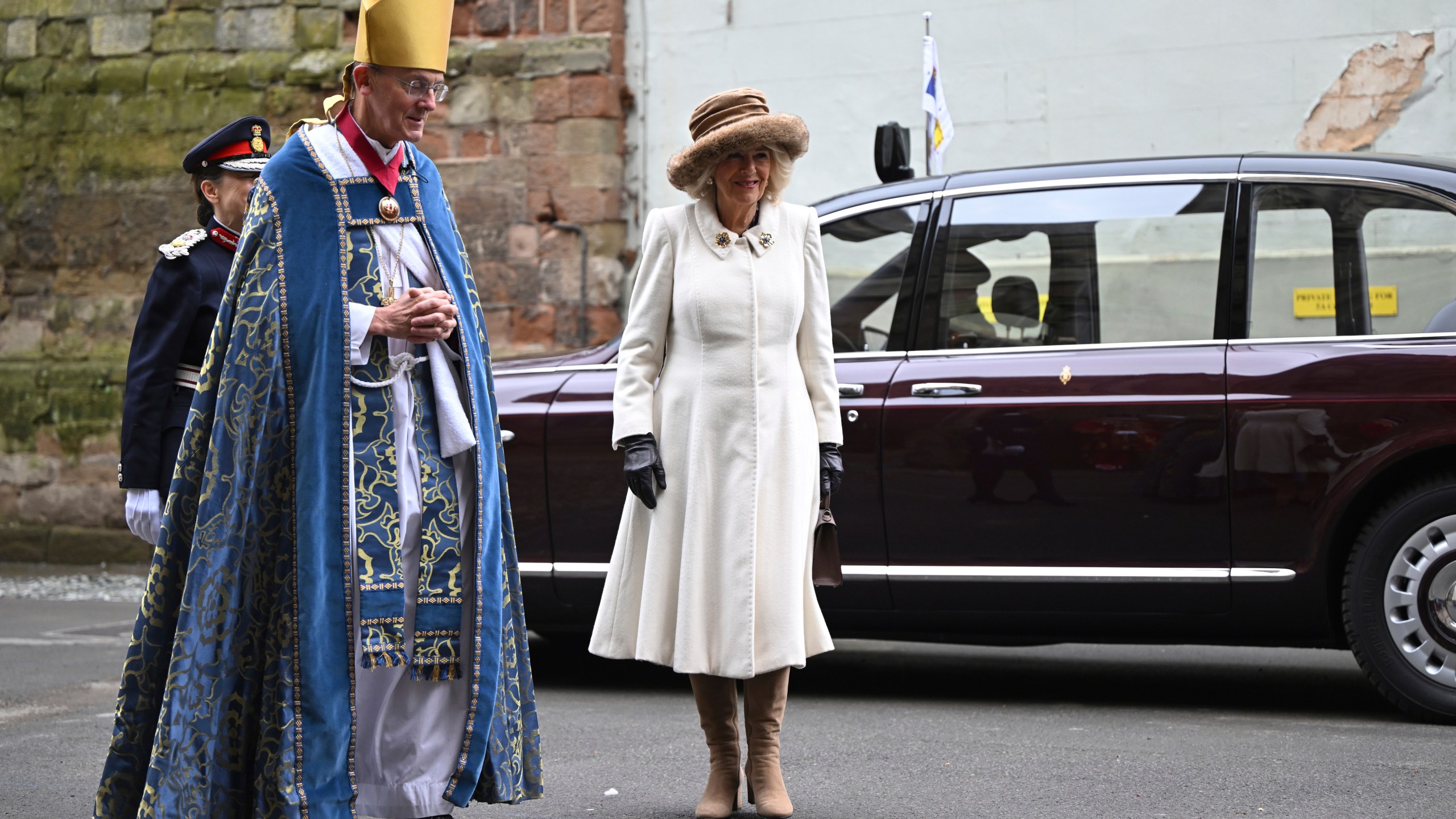 Britain's Queen Camilla is greeted by Bishop of Worcester Cathedral, The Right Reverend Dr John Inge, left, as she arrives for the Royal Maundy Service where she distributes the Maundy money to 75 men and 75 women, mirroring the age of the monarch, in Worcester Cathedral, Worcester, England, Thursday, March 28, 2024 to thank them for their outstanding Christian service and for making a difference to the lives of people in their local communities. Maundy Thursday is the Christian holy day falling on the Thursday before Easter. The monarch commemorates Maundy by offering 'alms' to senior citizens. Each recipient receives two purses, one red and one white. (Justin Tallis, Pool Photo via AP)