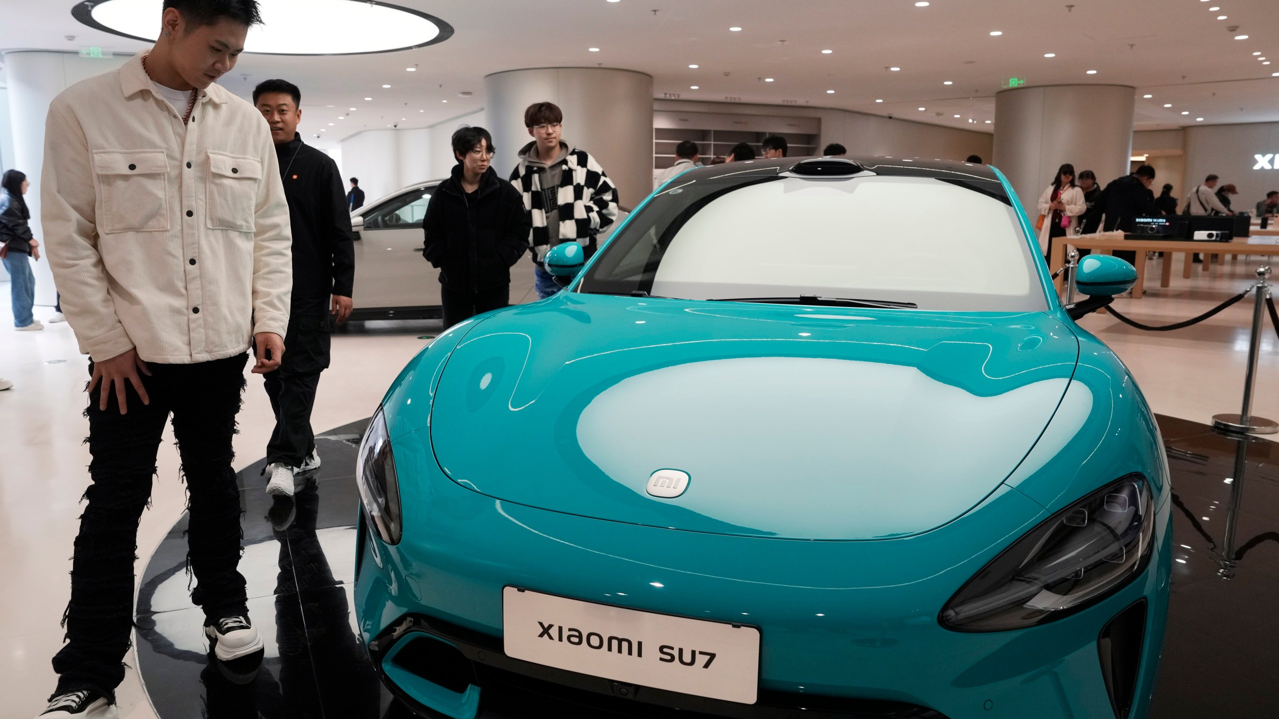 Visitors to the Xiaomi Automobile flagship store looks at the Xiaomi SU7 electric car on display in Beijing, Tuesday, March 26, 2024. Chinese smartphone maker Xiaomi announced that it will deliver its first electric vehicle on March 28, 2024. (AP Photo/Ng Han Guan)
