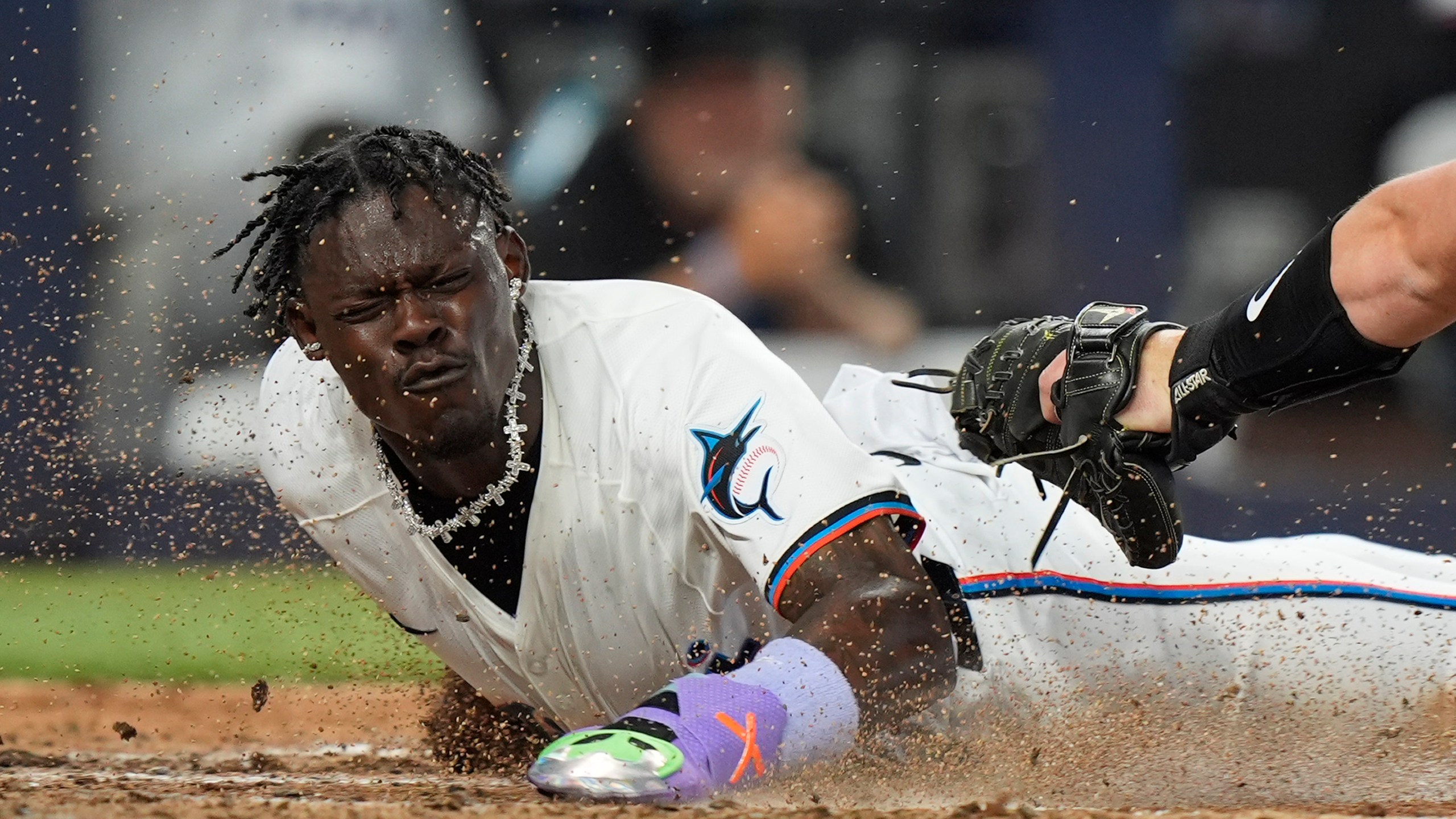 Miami Marlins' Jazz Chisholm Jr., left, scores as Pittsburgh Pirates catcher Henry Davis (32) attempts the tag, during the third inning of a baseball game, Thursday, March 28, 2024, in Miami. Bryan De La Cruz also scored on the single by Jake Burger. (AP Photo/Wilfredo Lee)