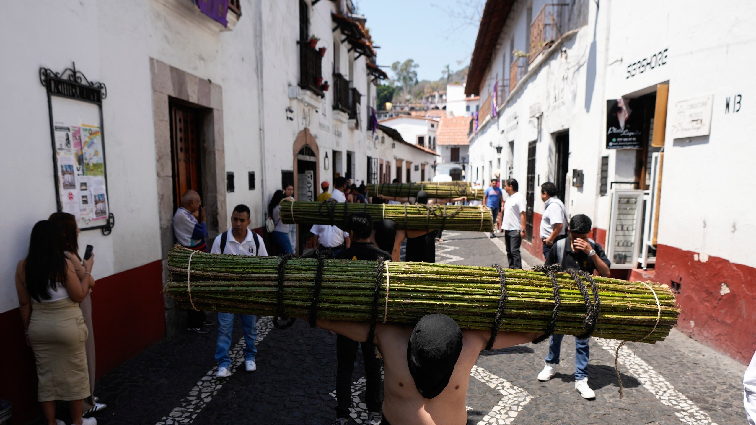Penitents carry a bundle of thorny branches during a Holy Week procession in Taxco, Mexico, Thursday, March 28, 2024. In traditional processions that last from Thursday evening into the early morning hours of Friday, hooded penitents drag chains and shoulder the thorny bundles through the streets, as some flog themselves with nail-studded whips meant to bring them closer to God. (AP Photo/Fernando Llano)