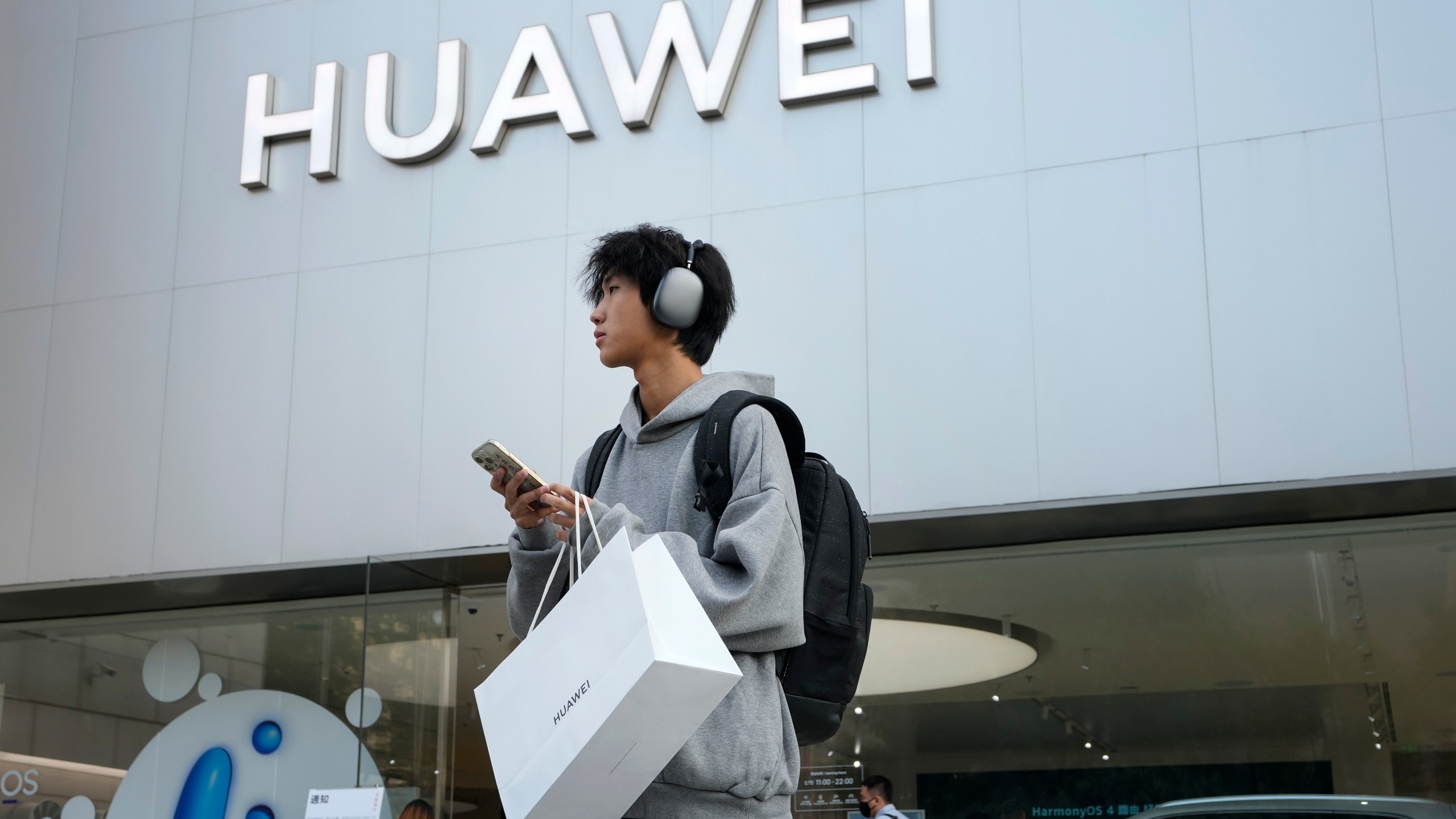 FILE - A customer carries his purchased Huawei product outside a Huawei store after he attended the Huawei new product launch conference in Beijing, on Sept. 25, 2023. Chinese telecoms gear company Huawei Technologies has reported its profit more than doubled last year as its cloud and digital businesses thrived in spite of U.S. sanctions. (AP Photo/Andy Wong, File)