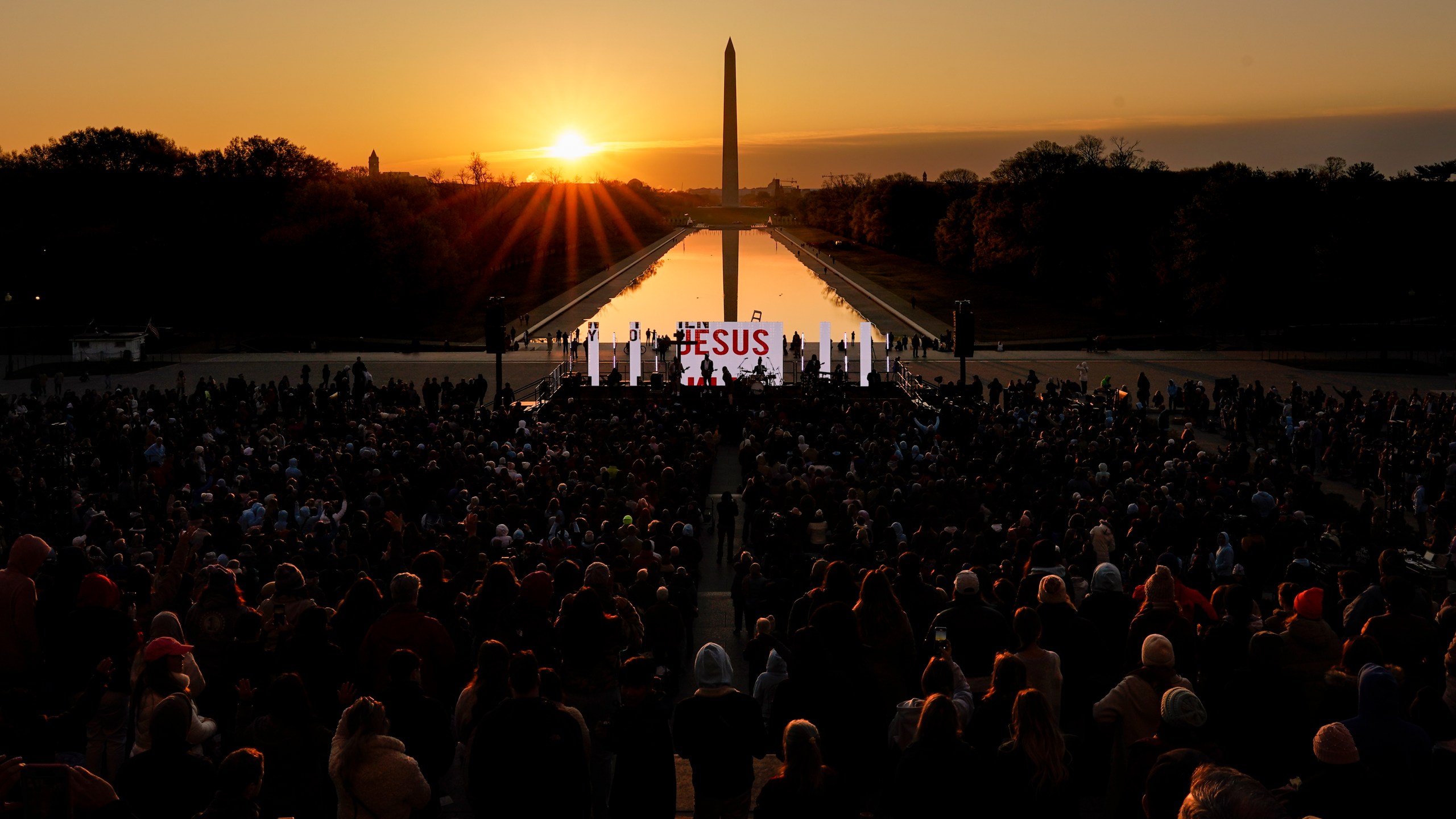 FILE - The word "Jesus" is displayed on a large monitor and worship songs are played on stage as people gather for the "Easter Sunrise Service" at the Lincoln Memorial, Sunday, April 9, 2023, in Washington, hosted by the National Community Church. On Easter morning, many Christians wake before dawn. They will celebrate their belief in the resurrection of Jesus, the son of God, as the sun rises. (AP Photo/Carolyn Kaster, File)