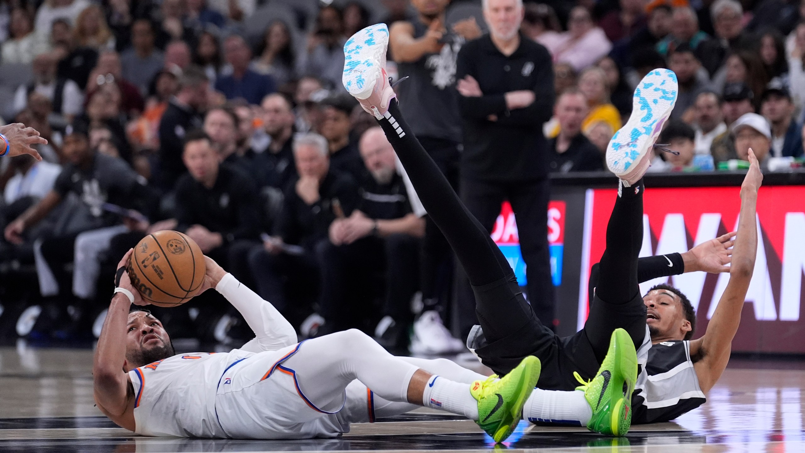 New York Knicks guard Jalen Brunson, left, look to pass the ball after he collided with San Antonio Spurs center Victor Wembanyama, right, during the second half of an NBA basketball game in San Antonio, Friday, March 29, 2024. (AP Photo/Eric Gay)