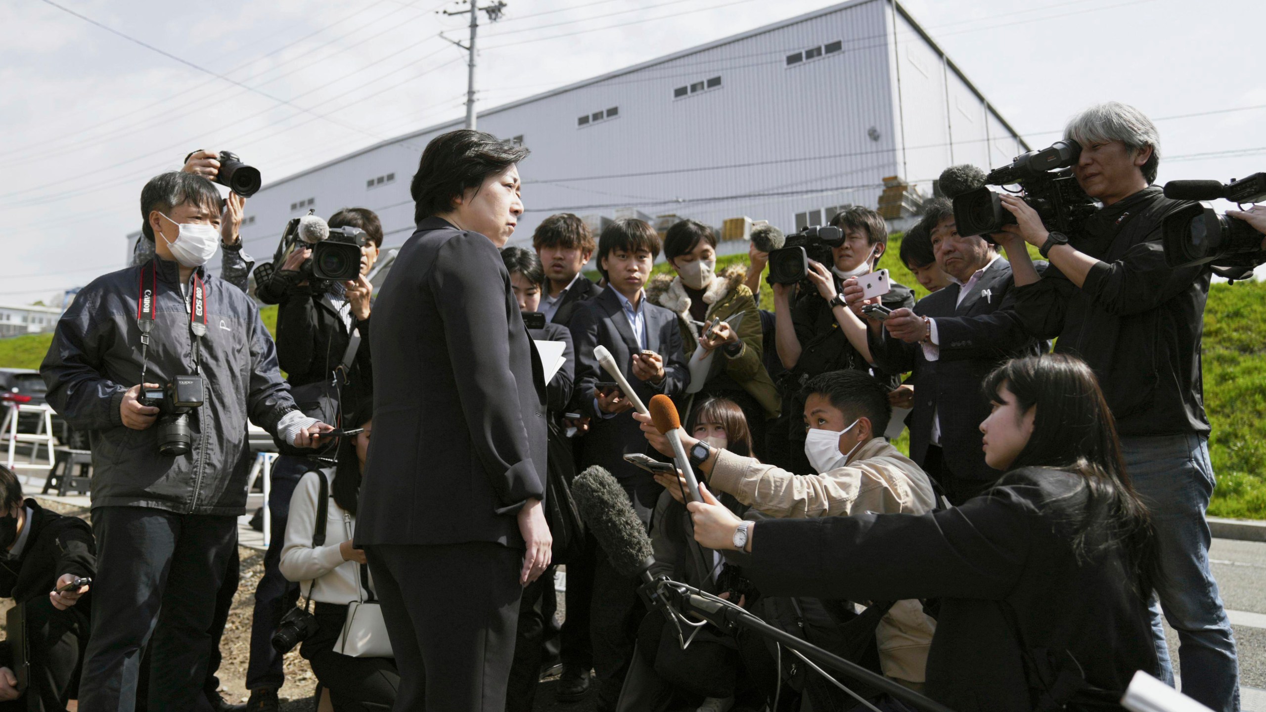 An employee of Kobayashi Pharmaceutical Co. speaks to media members outside a plant operated by its subsidiary after Japan's health ministry officials walked into the plant to conduct an on-site inspection in Kinokawa, south of Osaka, western Japan, Sunday, March 31, 2024. Japanese government health officials on Sunday inspected the factory producing health supplements linked to several deaths and the hospitalization of more than 100 others, one day after the authorities investigated another plant that manufactured the product. (Yohei Fukai/Kyodo News via AP)