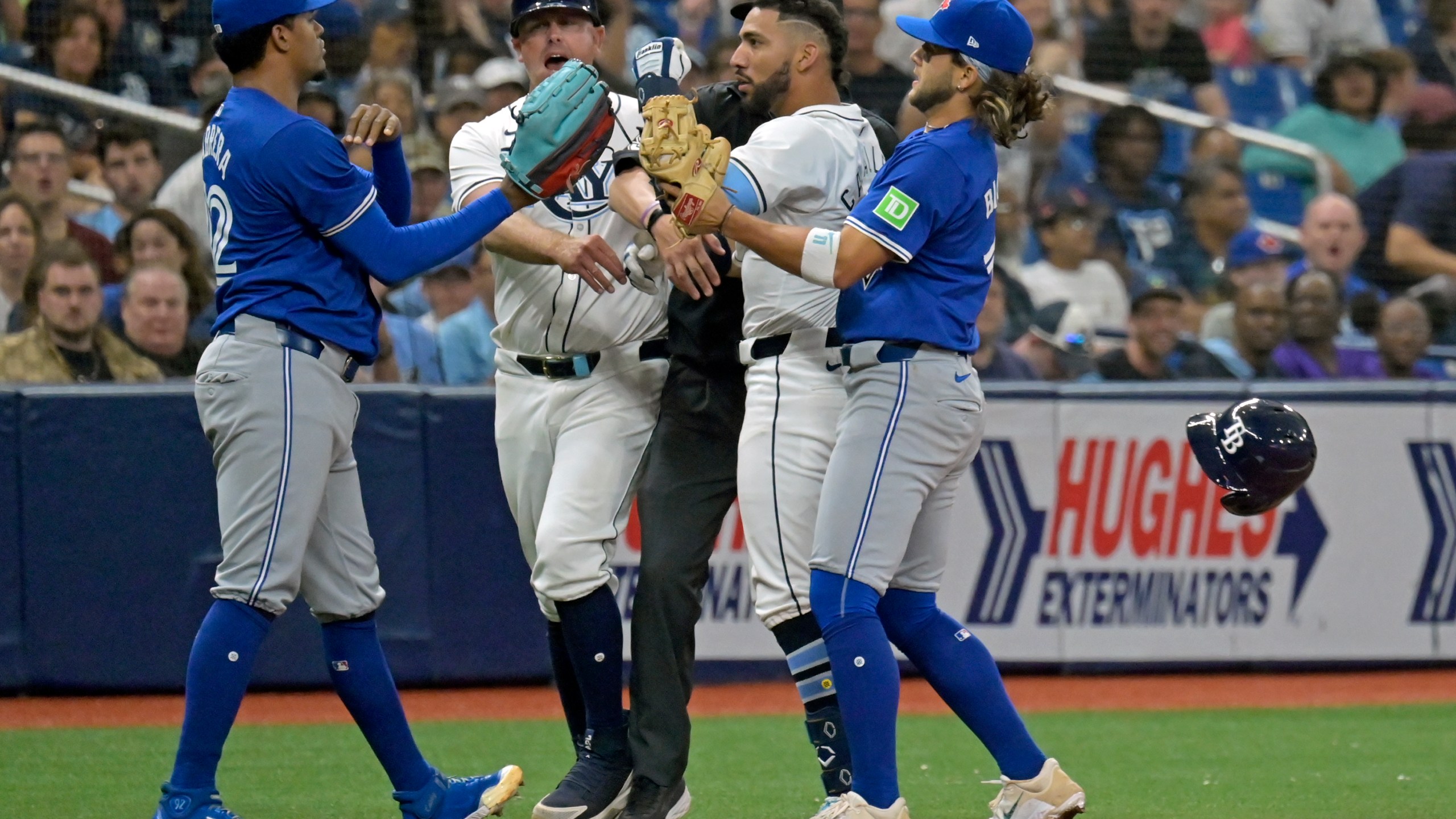 Tampa Bay Rays third base coach Brady Williams, center left, and Toronto Blue Jays shortstop Bo Bichette, right, try to break up a confrontation between Tampa Bay's Jose Caballero, center right, and Toronto Blue Jays reliever Genesis Cabrera, left, after Cabrera pushed Caballero during the seventh inning of a baseball game, Saturday, March 30, 2024, in St. Petersburg, Fla. (AP Photo/Steve Nesius)