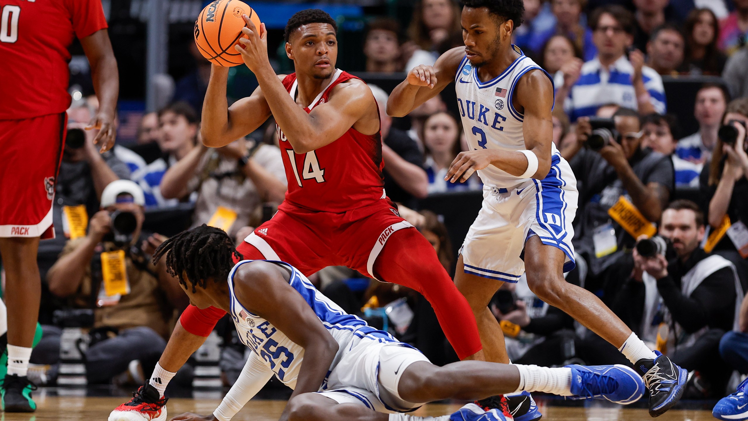 North Carolina State's Casey Morsell (14) keeps control of the ball while being pressured by Duke's Mark Mitchell (25) and Jeremy Roach (3) during the first half of an Elite Eight college basketball game in the NCAA Tournament in Dallas, Sunday, March 31, 2024. (AP Photo/Brandon Wade)