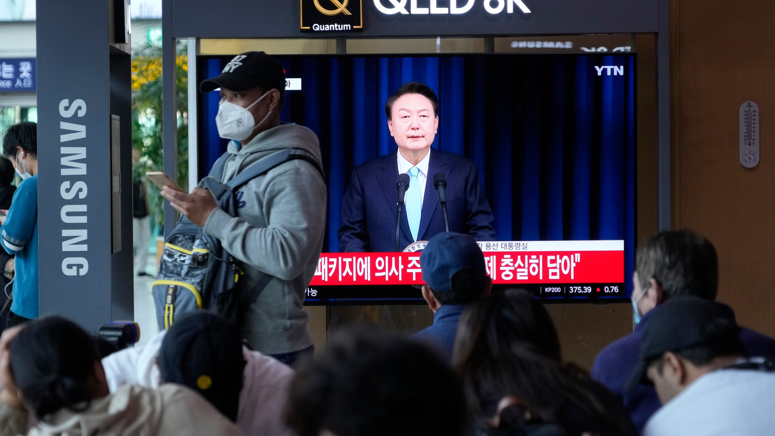 People watch a TV screen showing the live broadcast of South Korean President Yoon Suk Yeol’s addressing the nation at the Seoul Railway Station in Seoul, South Korea, Monday, April 1, 2024. President Yoon vowed Monday not to back down in the face of vehement protests by doctors seeking to spike his plan to drastically increase medical school admissions, as he called their walkouts “an illegal collective action” that poses "a grave threat to our society.” (AP Photo/Ahn Young-joon)