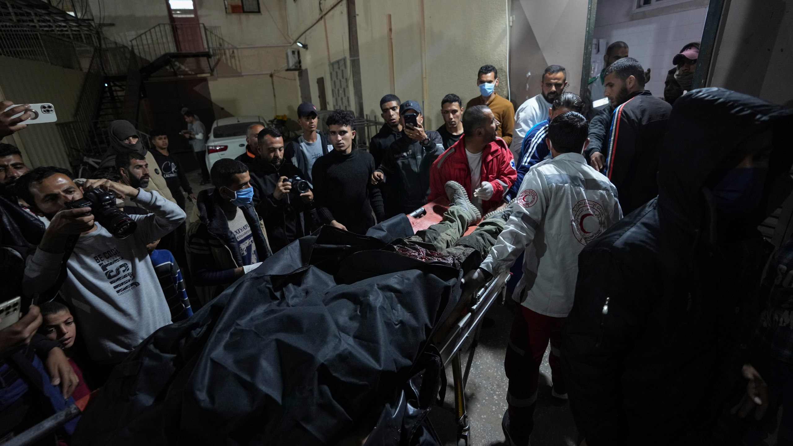 Palestinians carry the body of a person following an Israeli airstrike, into the Al Aqsa hospital in Deir al Balah, Gaza Strip, Monday, April 1, 2024. Gaza medical officials say an apparent Israeli airstrike killed four international aid workers with the World Central Kitchen charity and their Palestinian driver after they helped deliver food and other supplies to northern Gaza that had arrived hours early by ship. (AP Photo/Abdel Kareem Hana)